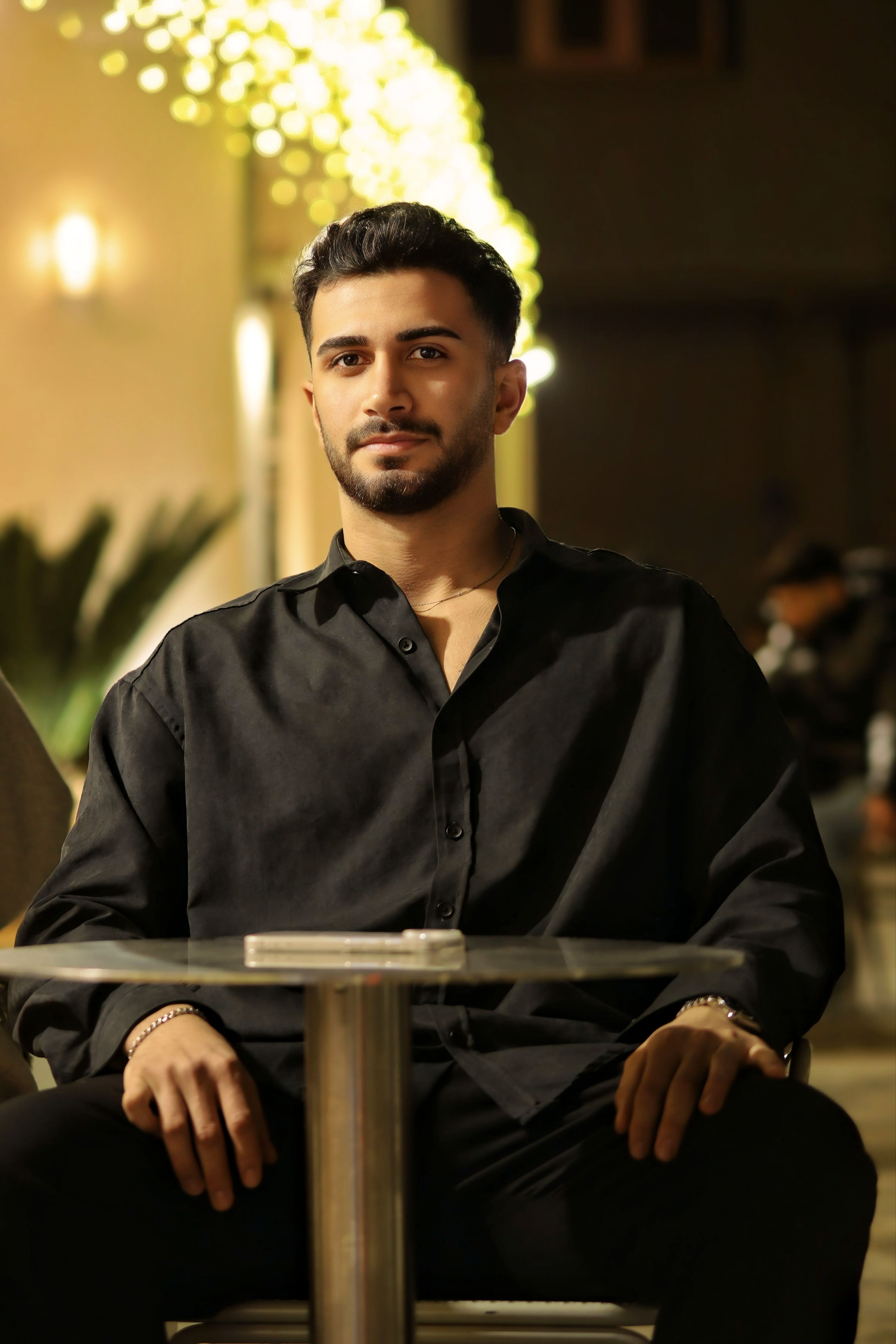 Portrait of a young man casually seated outdoors at a nighttime café.