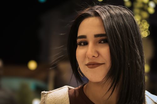 Free Close-up outdoor portrait of a smiling woman at night with blurred lights in the background. Stock Photo