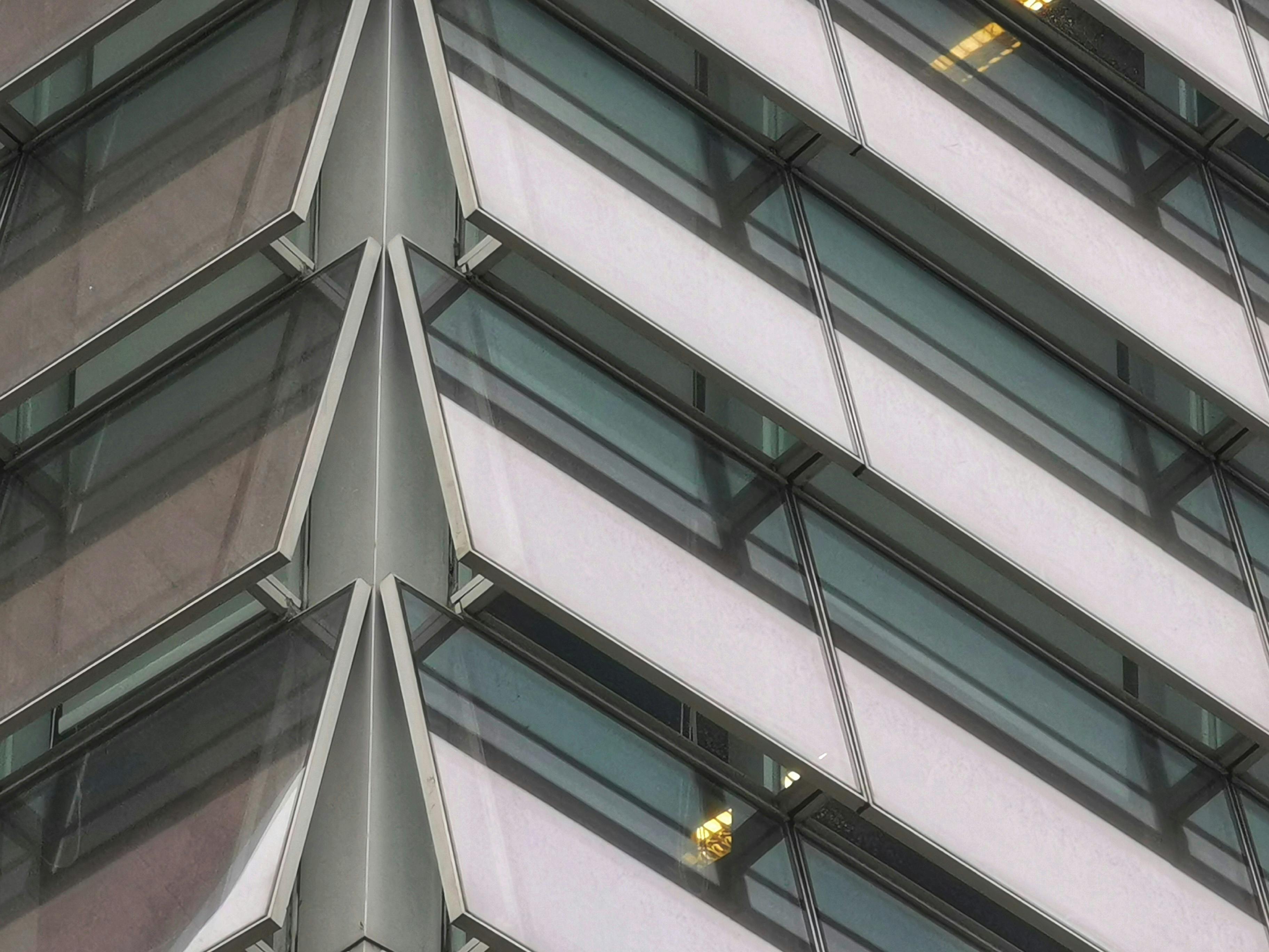 Gratis Fasad geometris yang mencolok dari bangunan modern dengan panel kaca dan fitur bersudut. Foto Stok