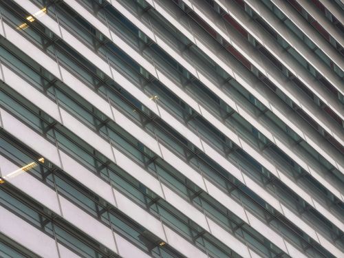 Free Diagonal view of a modern office building facade showcasing glass windows and sleek design. Stock Photo
