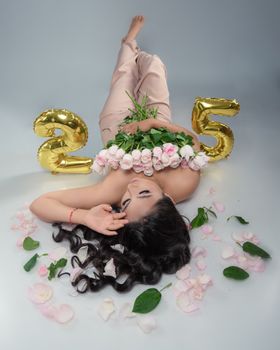 Elegant portrait of a woman celebrating her 25th birthday with flowers and gold balloons.