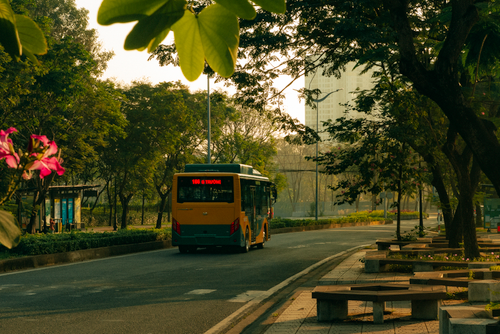 Free A city bus travels along a tree-lined street in Ho Chi Minh City, Vietnam. Vibrant and serene setting. Stock Photo
