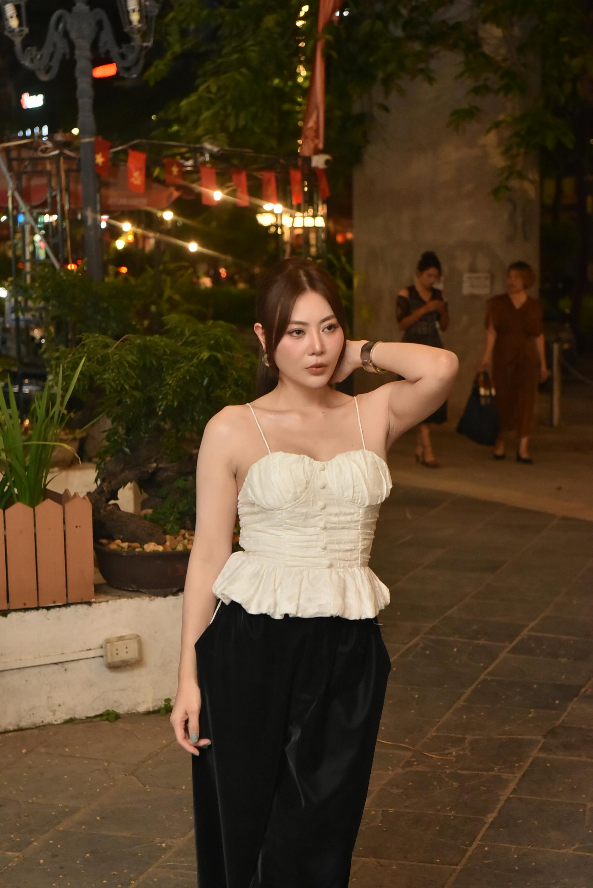 Gratis Mujer asiática con atuendo elegante de pie al aire libre en un mercado nocturno con luces. Foto de stock