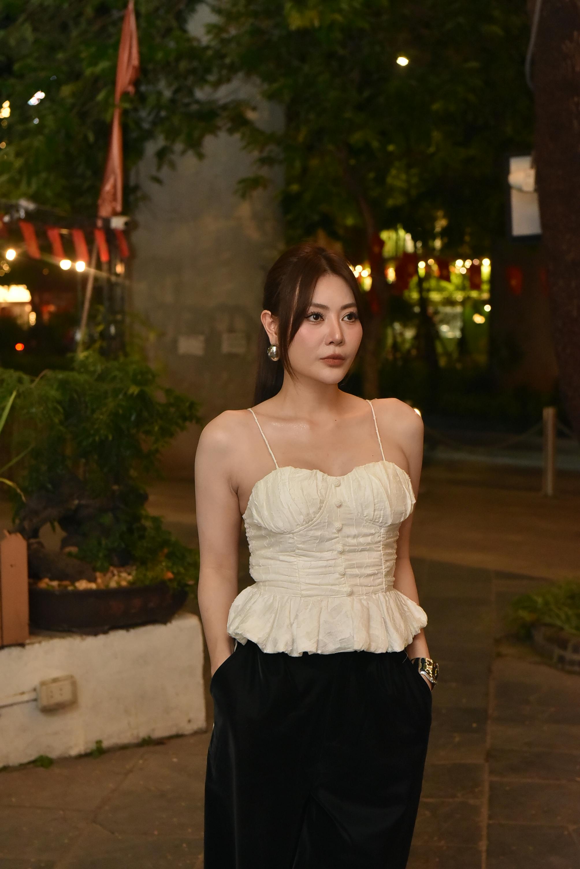 grátis Mulher jovem e elegante de blusa branca posando ao ar livre à noite com as luzes da cidade. Foto profissional