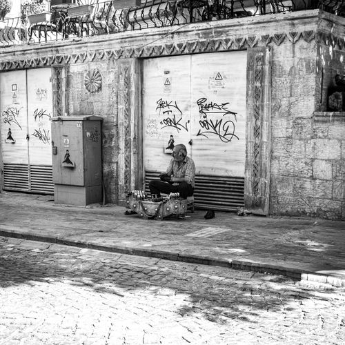 Free A lone street vendor sits quietly in an urban setting, selling goods. Stock Photo
