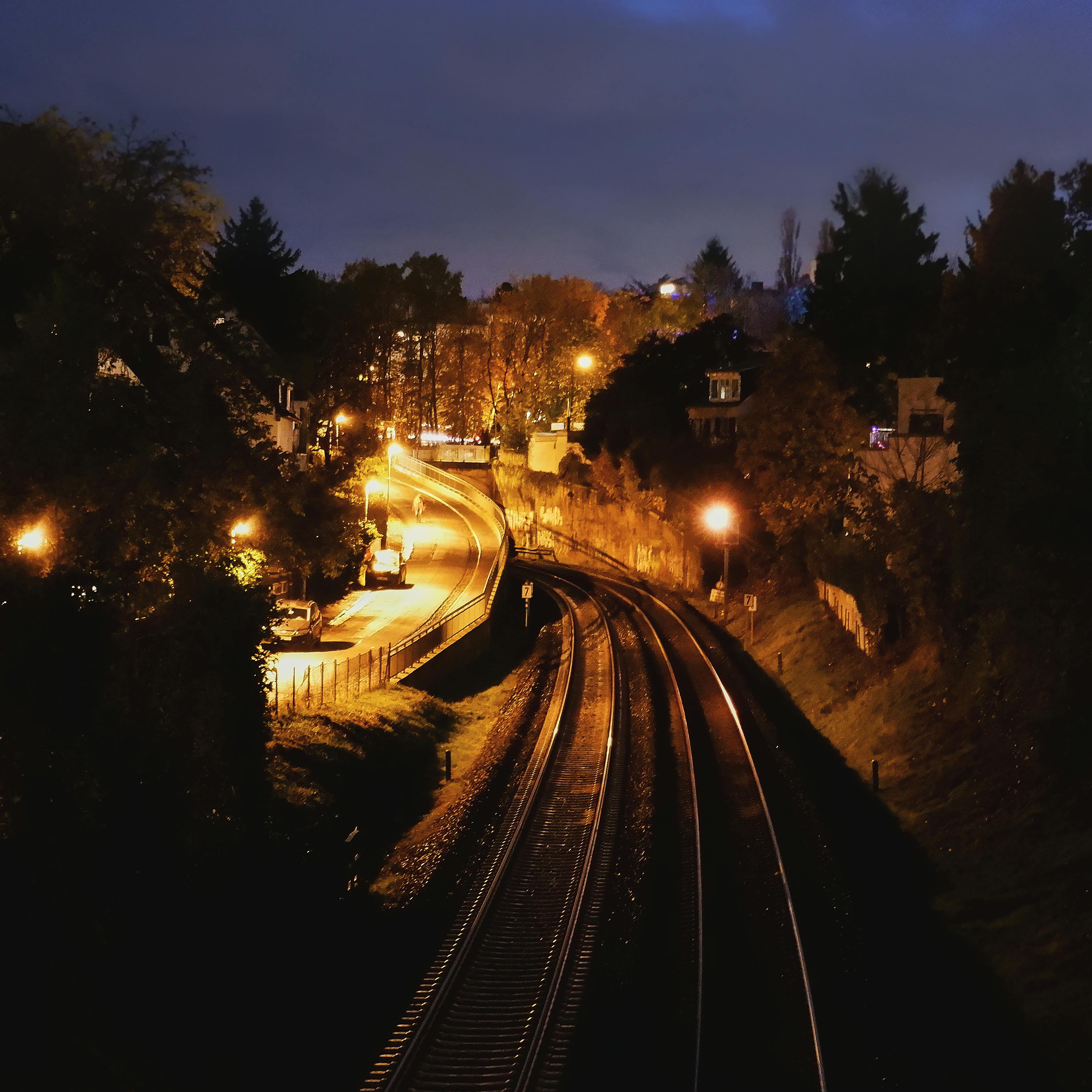 A serene nighttime view of a quiet railway in Darmstadt with warm streetlights and autumn colors.