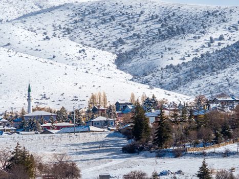 Scenic view of a charming village nestled in snowy mountains, highlighting serene winter beauty.