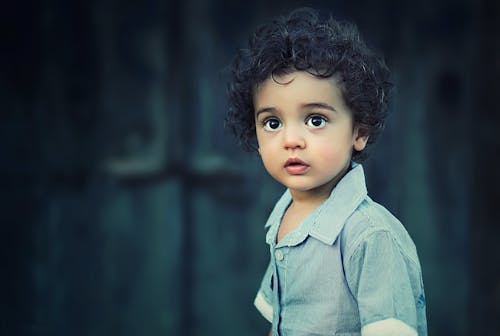 Toddle Mengenakan Kemeja Berkerah Kancing Abu Abu Dengan Rambut Keriting