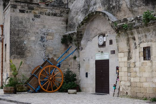 Old stone building with a vintage cart and doorway in an Italian village street scene.