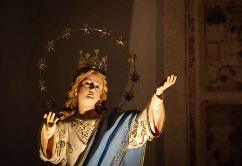 Free Close-up of a decorative religious statue with a starry halo inside a church, emphasized by warm lighting. Stock Photo