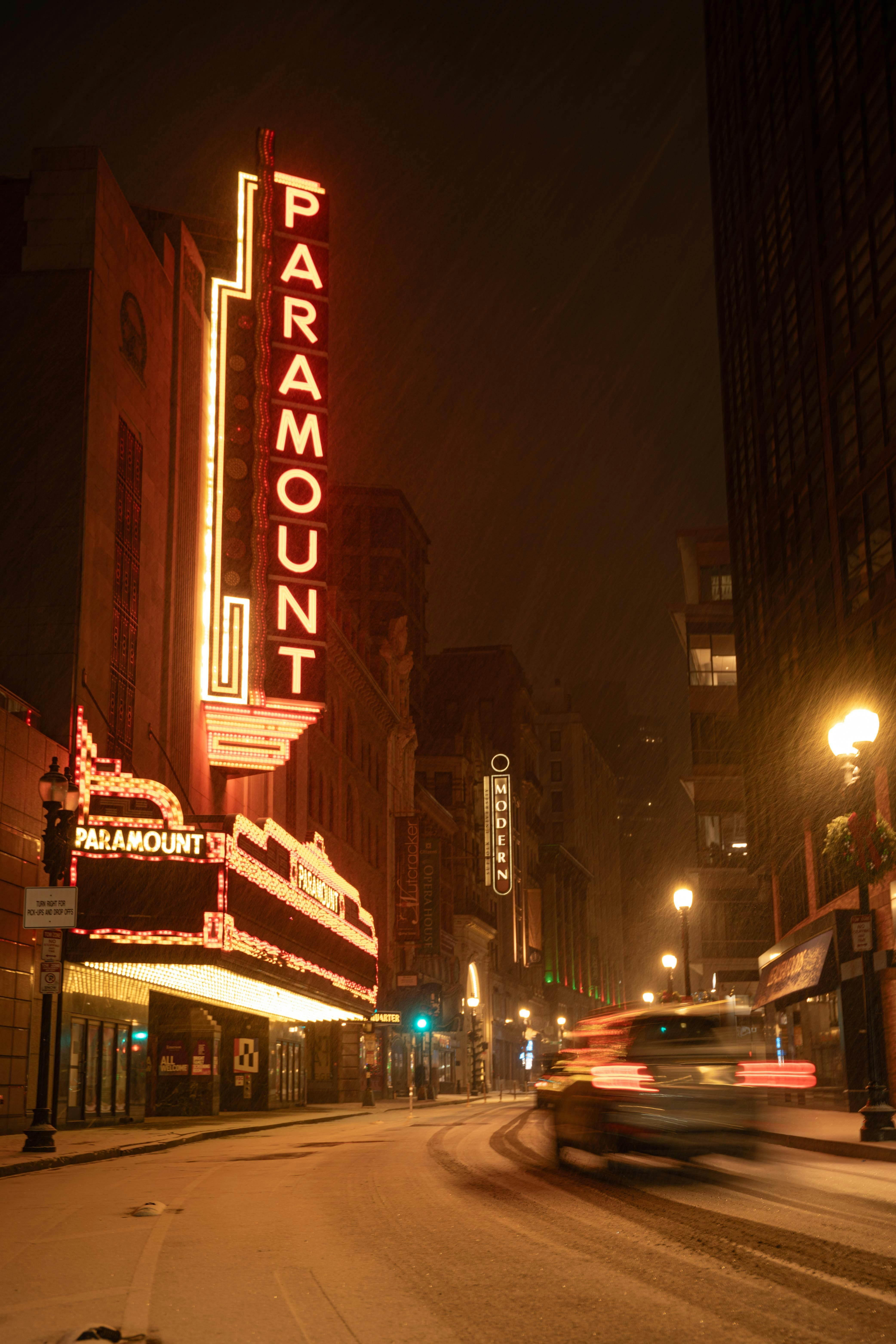 Gratuit La vie nocturne de la ville immortalisée par les néons du Paramount Theatre sur fond de rue enneigée. Photos