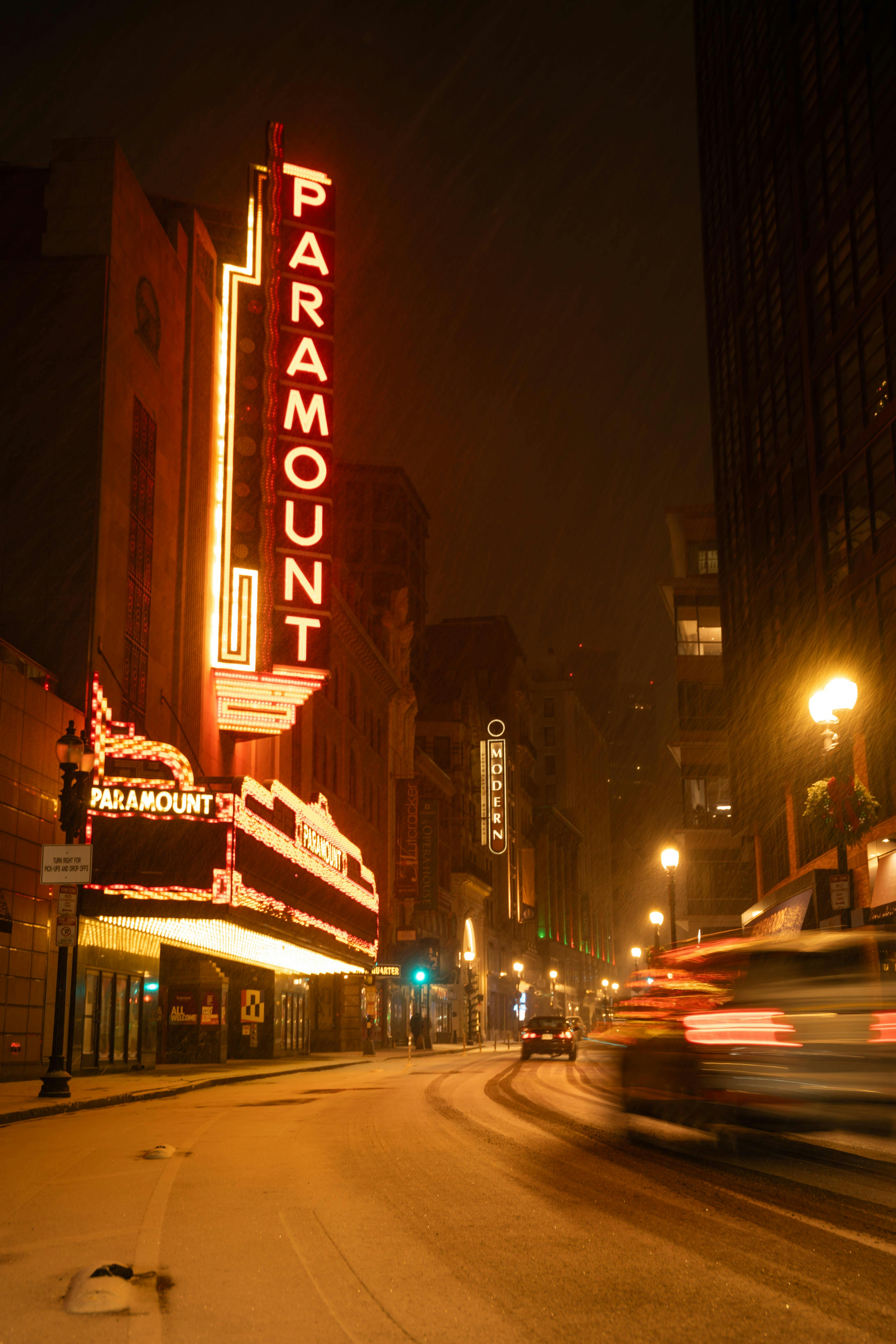 Bezpłatne Jaskrawe światła neonów rozświetlają Teatr Paramount w tętniącą życiem miejską noc. Zdjęcie z galerii