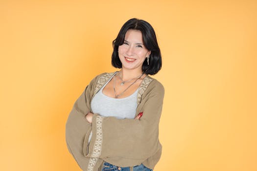 Donna sicura di sé con i capelli corti che sorride su uno sfondo giallo brillante.