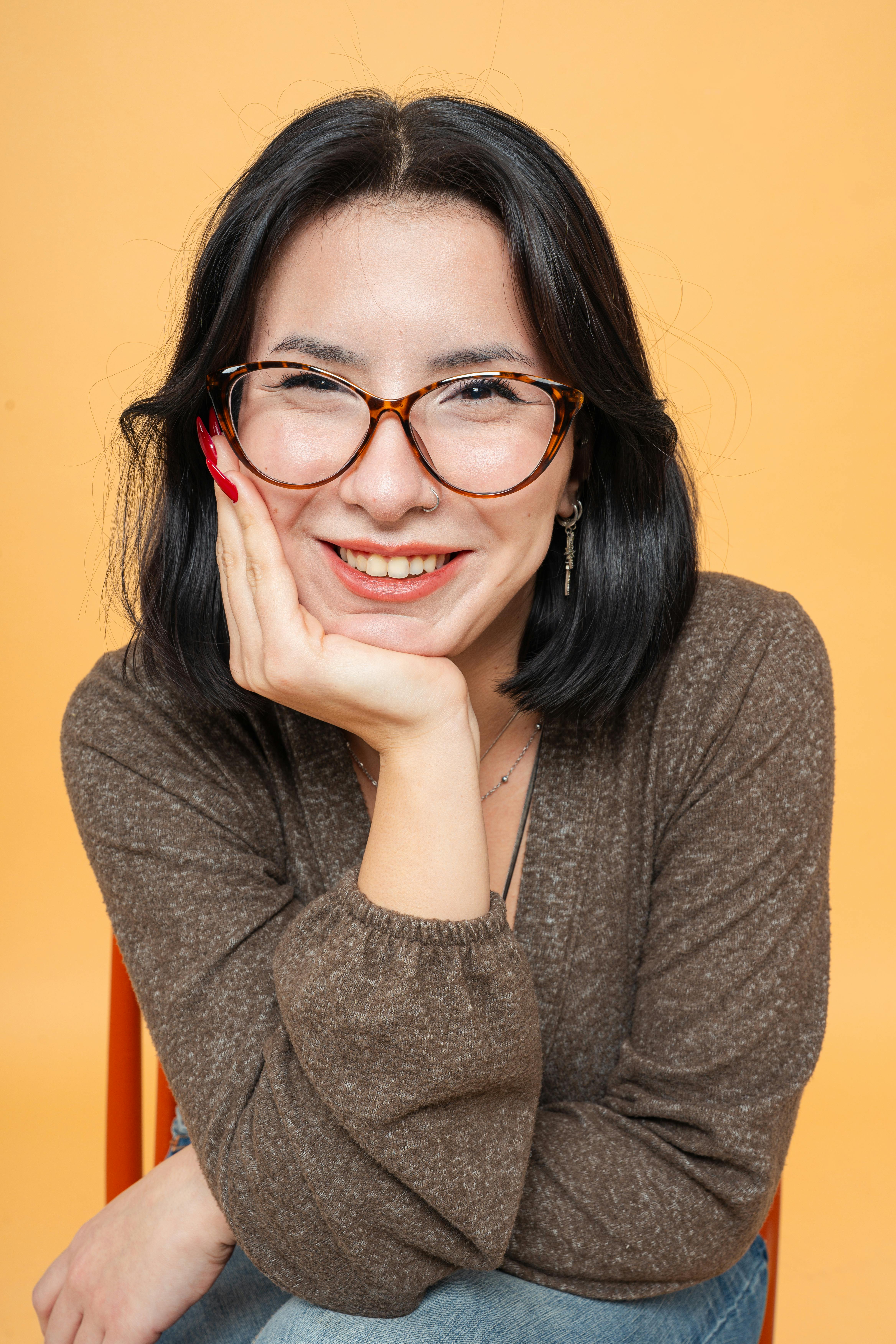 De franc Retrat d'una dona somrient amb ulleres posant sobre un fons taronja vibrant a Yalova, Turquia. Foto d'estoc