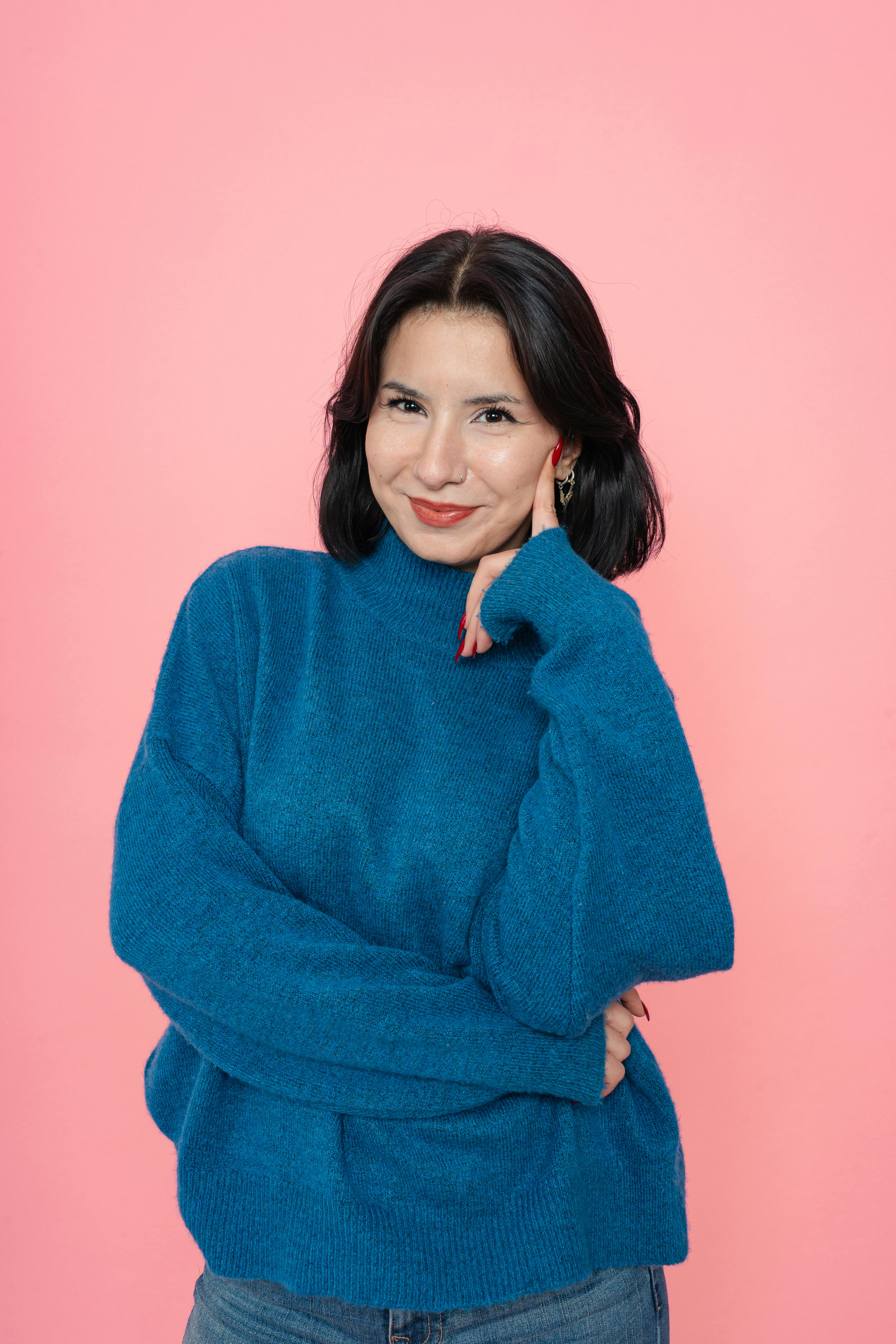 De franc Retrat d'una dona somrient amb un jersei blau sobre un fons rosa, que traspua calidesa i confiança. Foto d'estoc