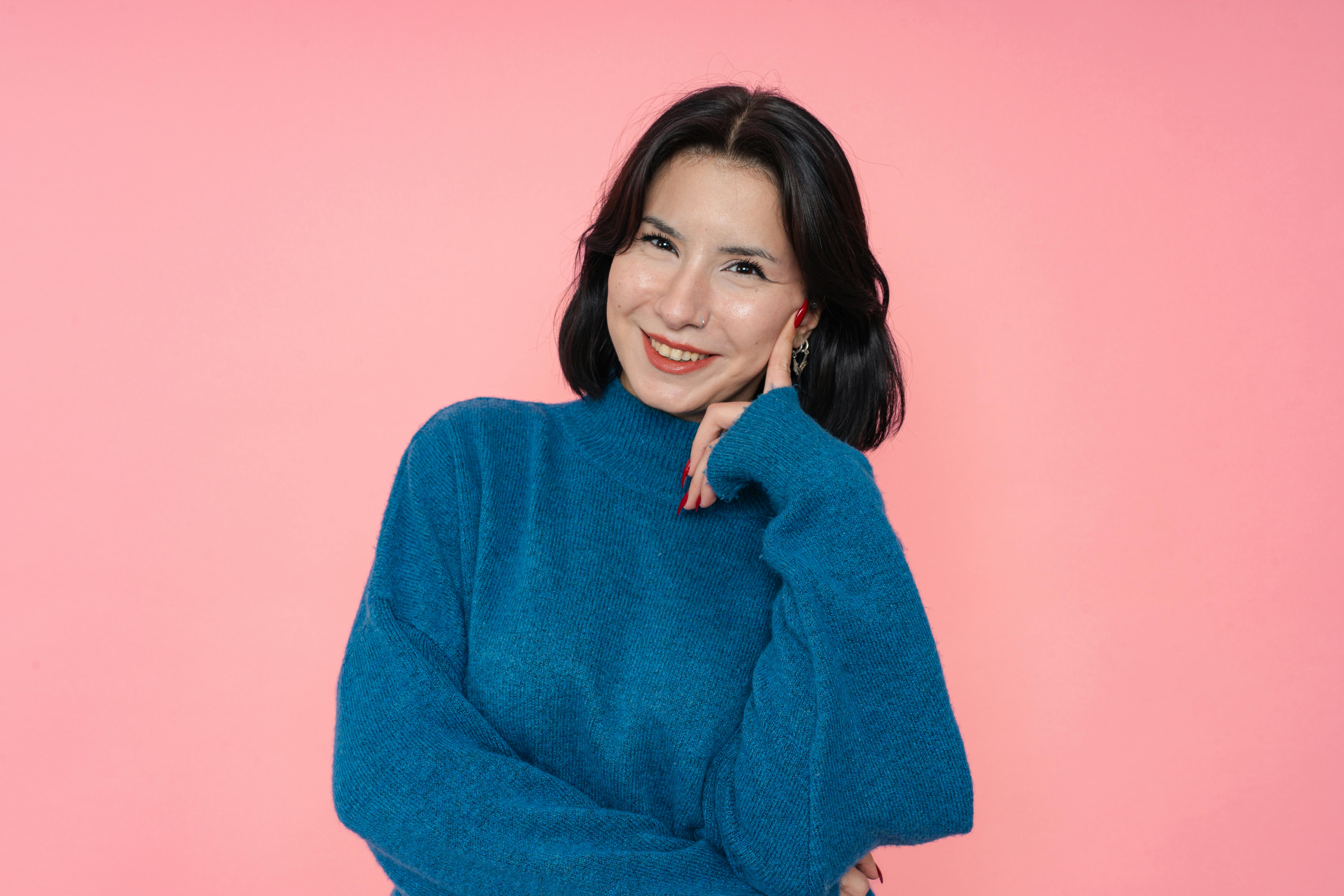 De franc Retrat d'una dona somrient amb un jersei blau sobre un fons rosa vibrant. Foto d'estoc