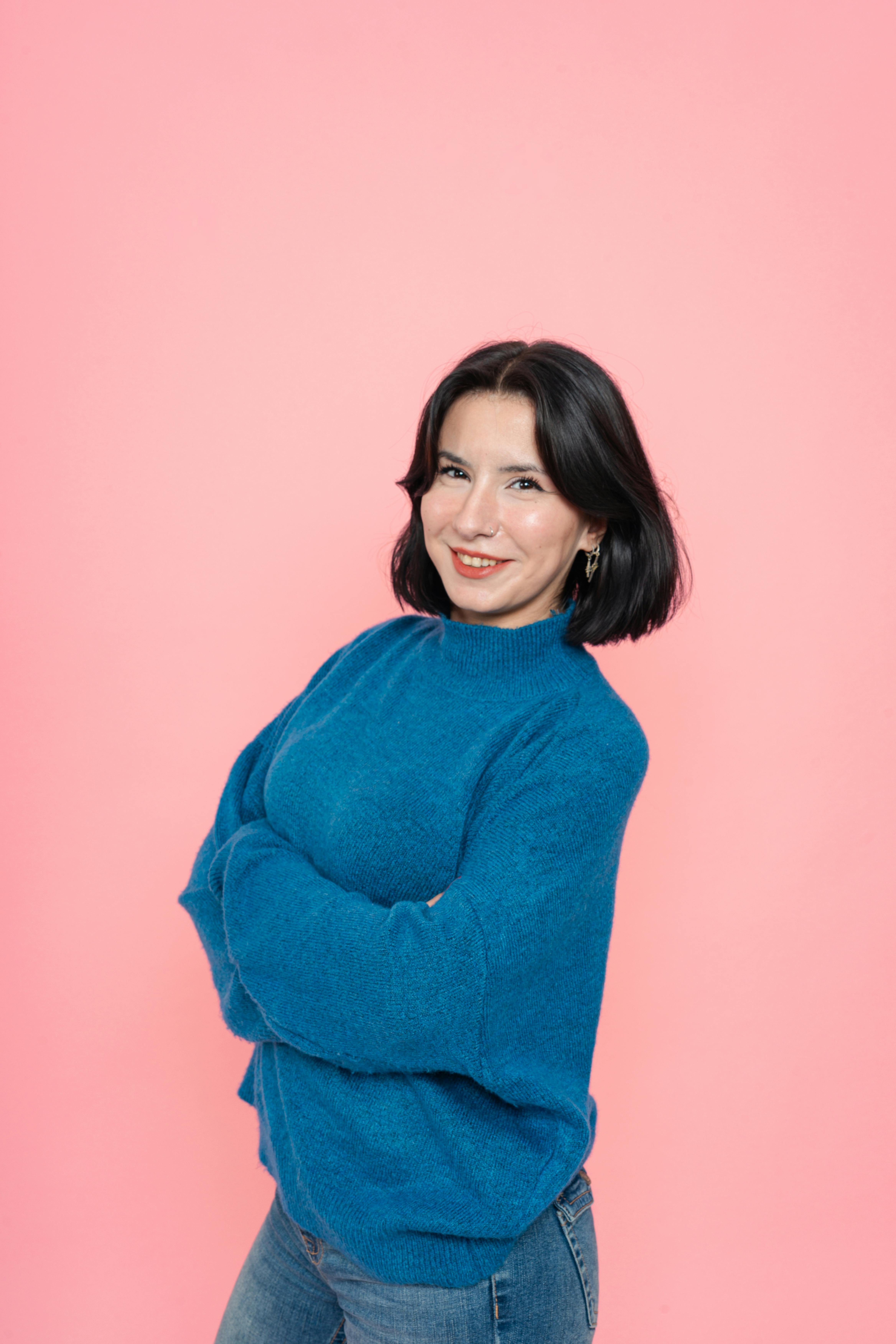 De franc Dona segura de si mateixa posant amb un jersei blau sobre un fons rosa vibrant. Foto d'estoc