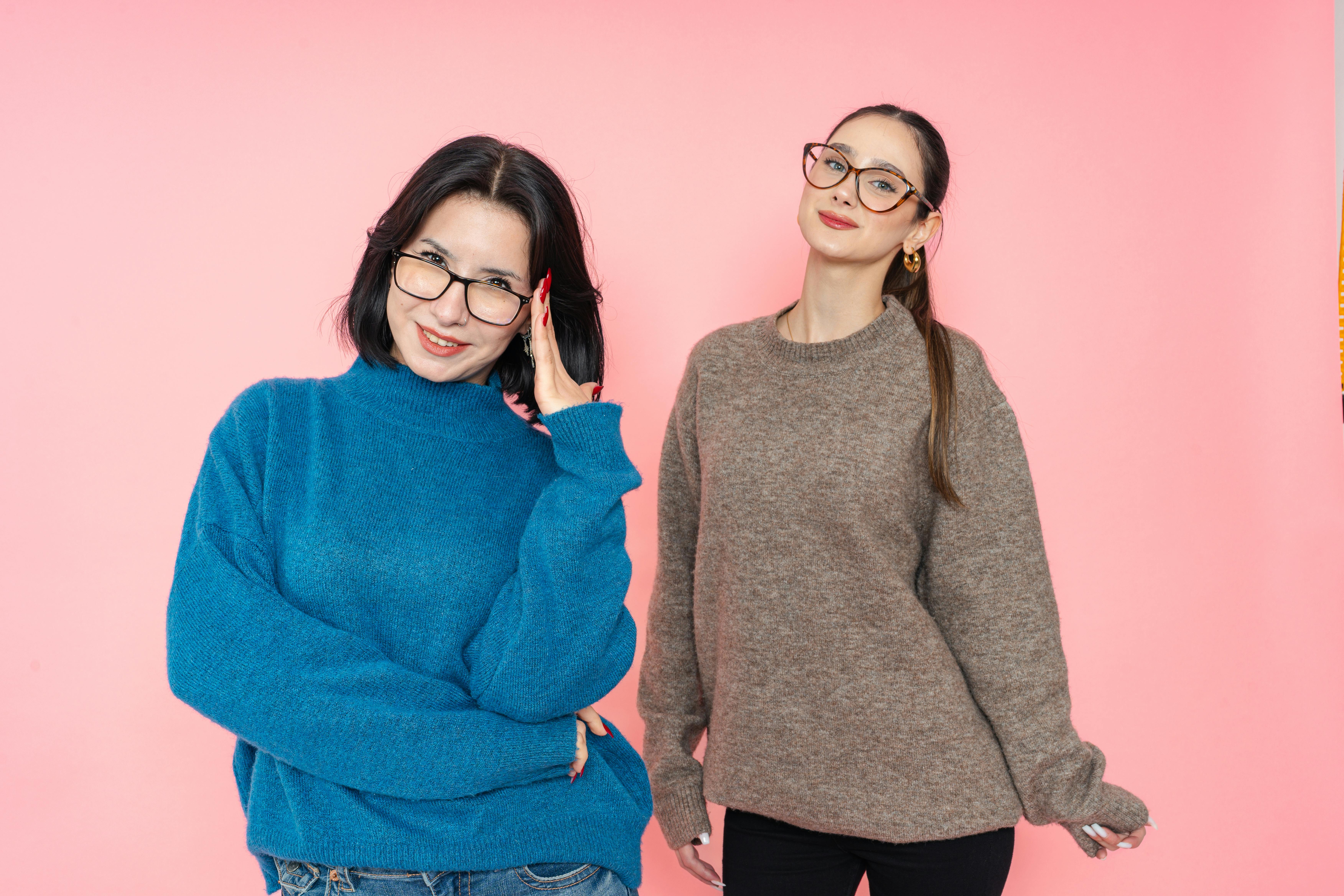 De franc Dues dones amb jerseis elegants posant sobre un fons rosa. Foto d'estoc