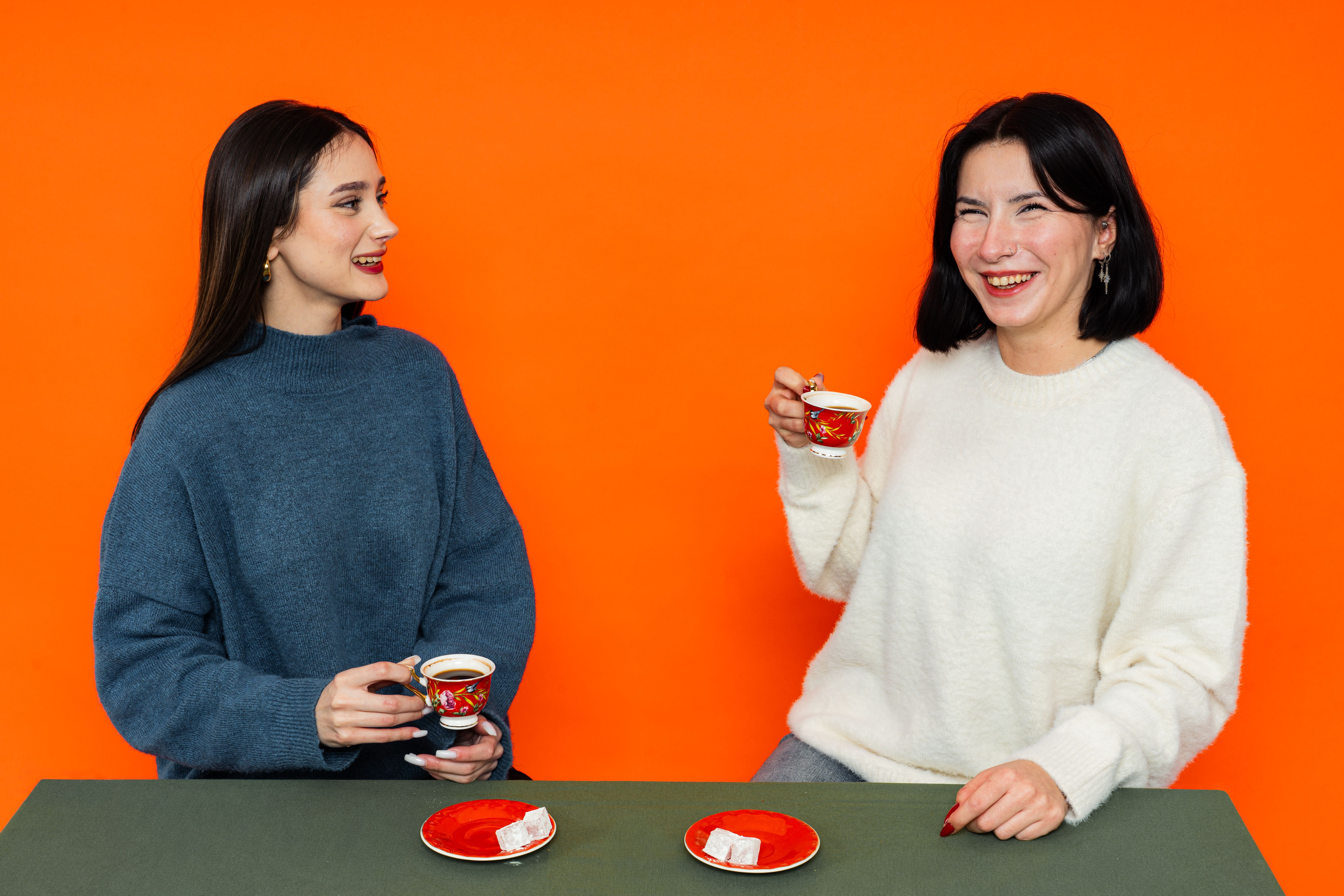 Two women enjoying Turkish coffee in a cozy setting with colorful background.