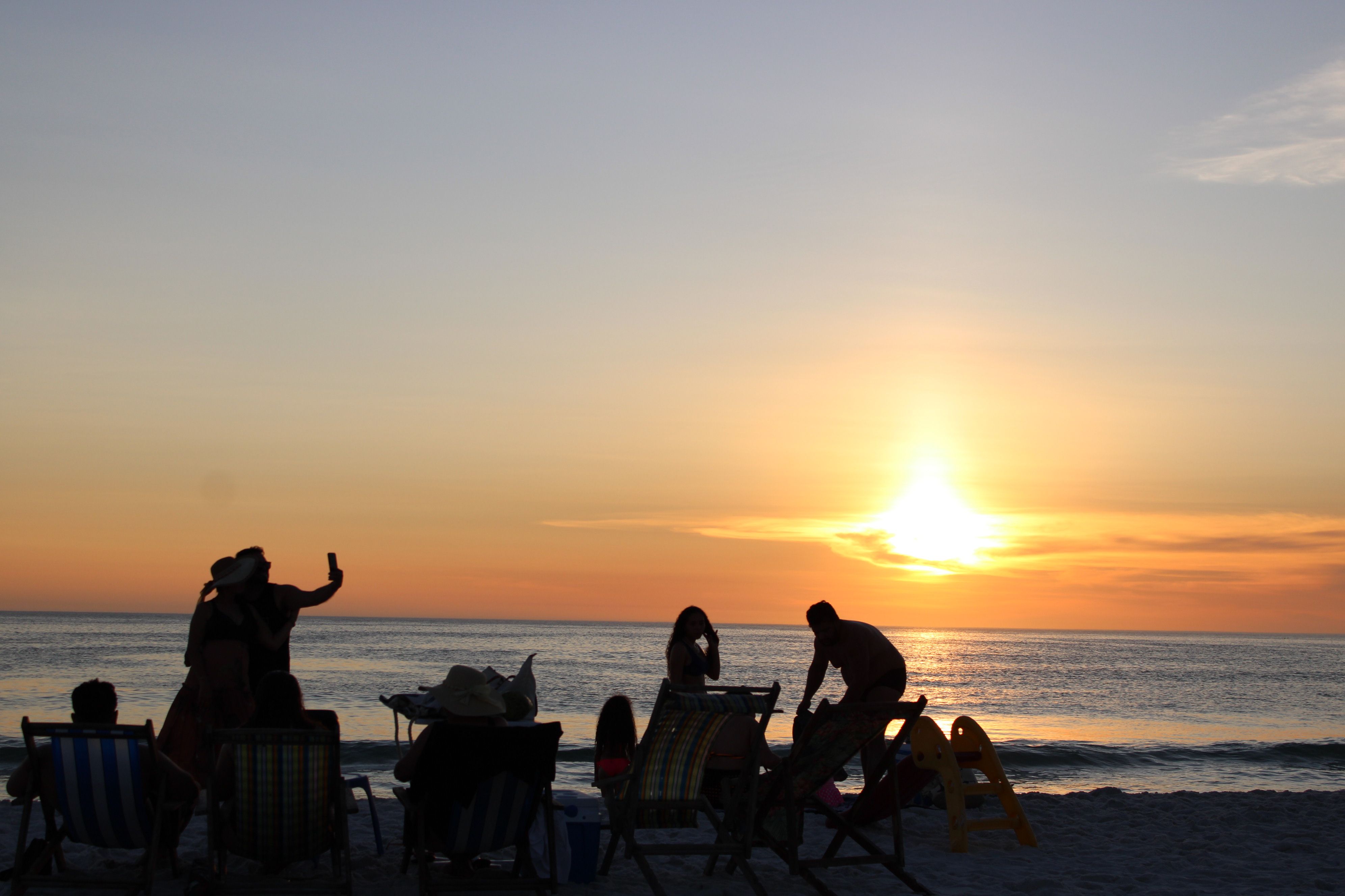 Gratis Silhuet af mennesker, der nyder en rolig solnedgang på stranden. Lagerfoto