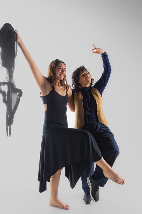 Free Two women performing expressive dance poses in a studio with subtle lighting. Stock Photo