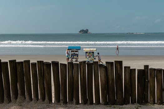 Vibrant beach scene with vendors, ocean waves, and distant island view.