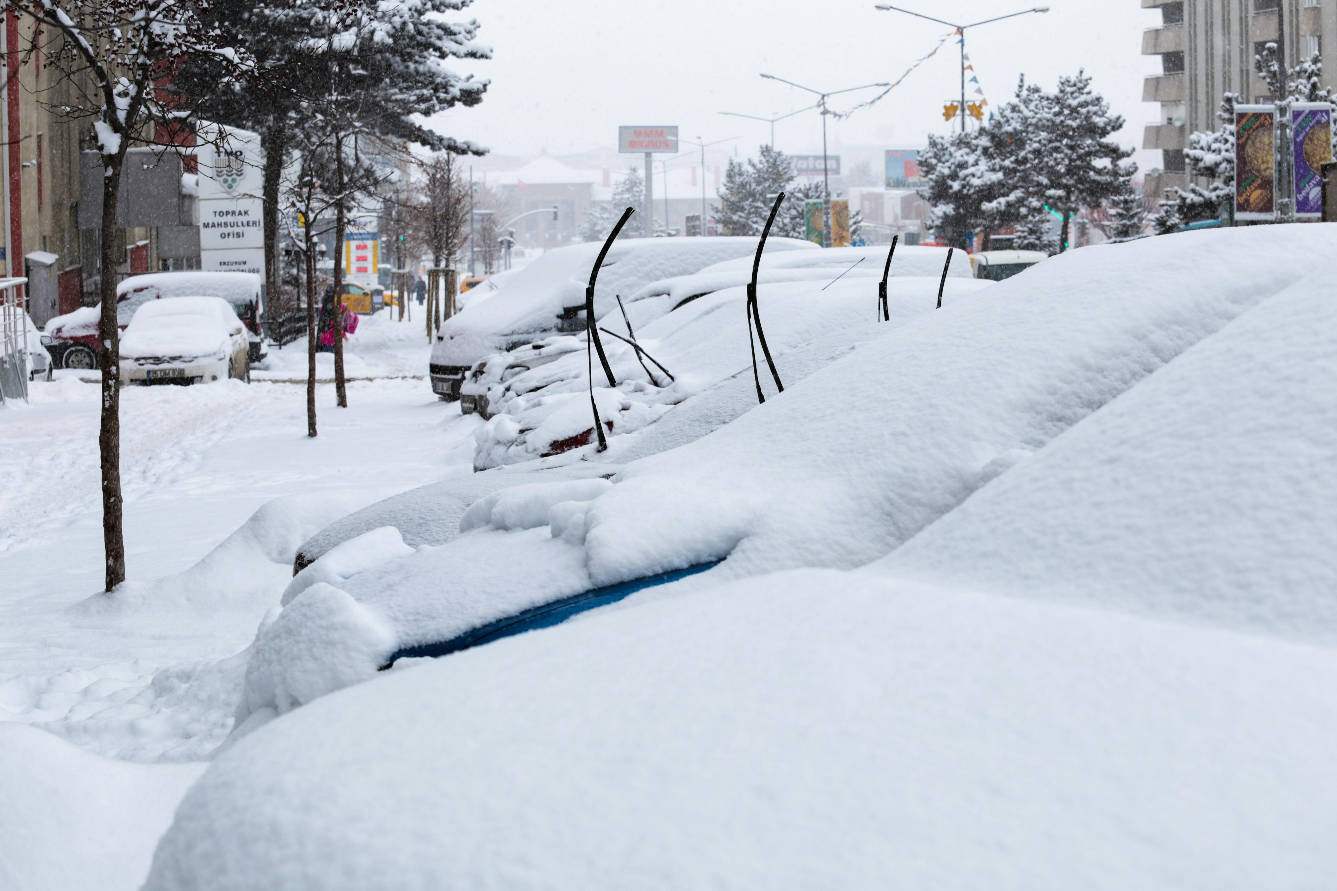 Snow-covered cars and streets in Niğde, Türkiye during a winter day.
