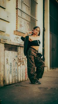 Stylish woman posing in urban setting with graffiti walls.