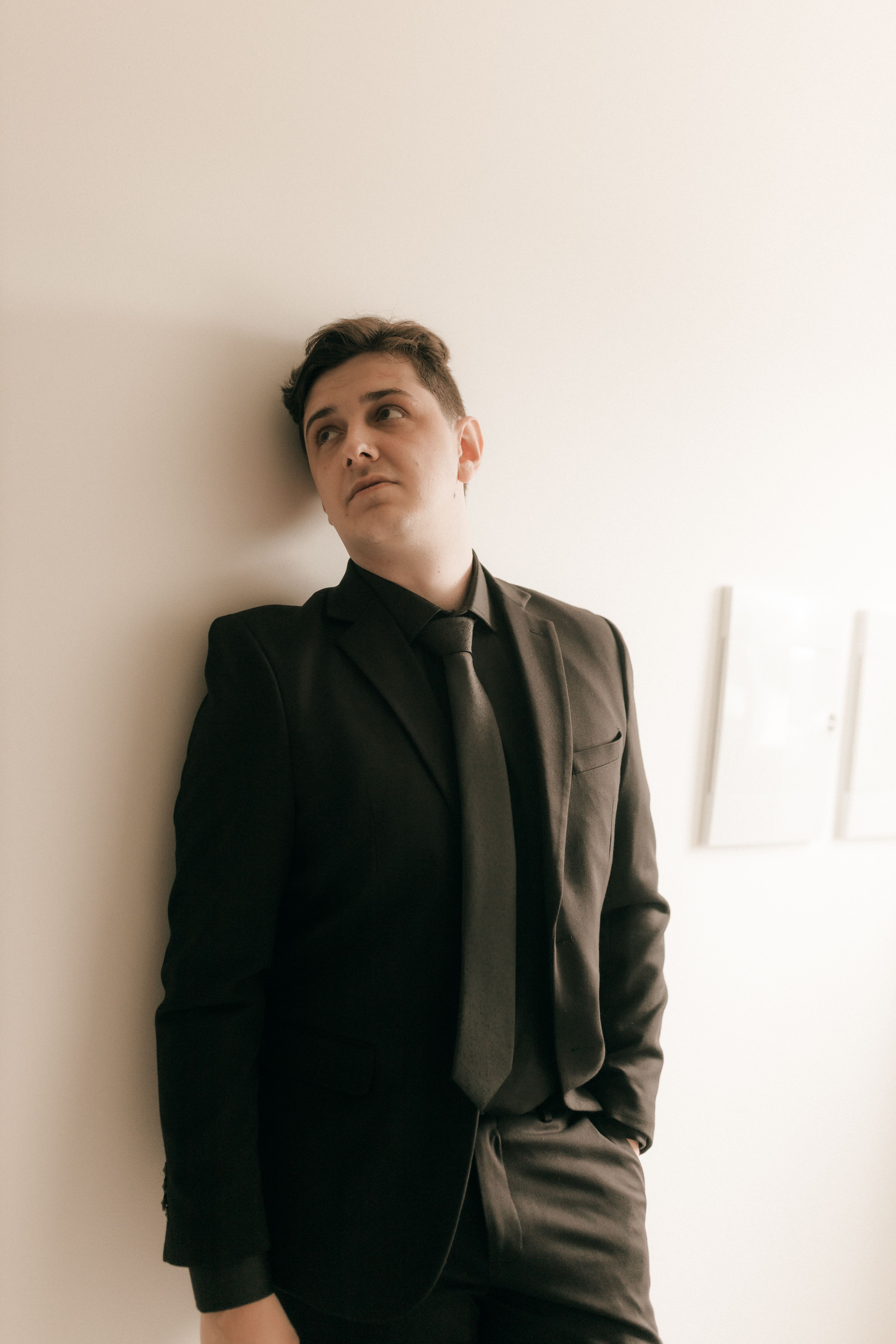 Man in Suit Leaning Against a Wall Indoors · Free Stock Photo