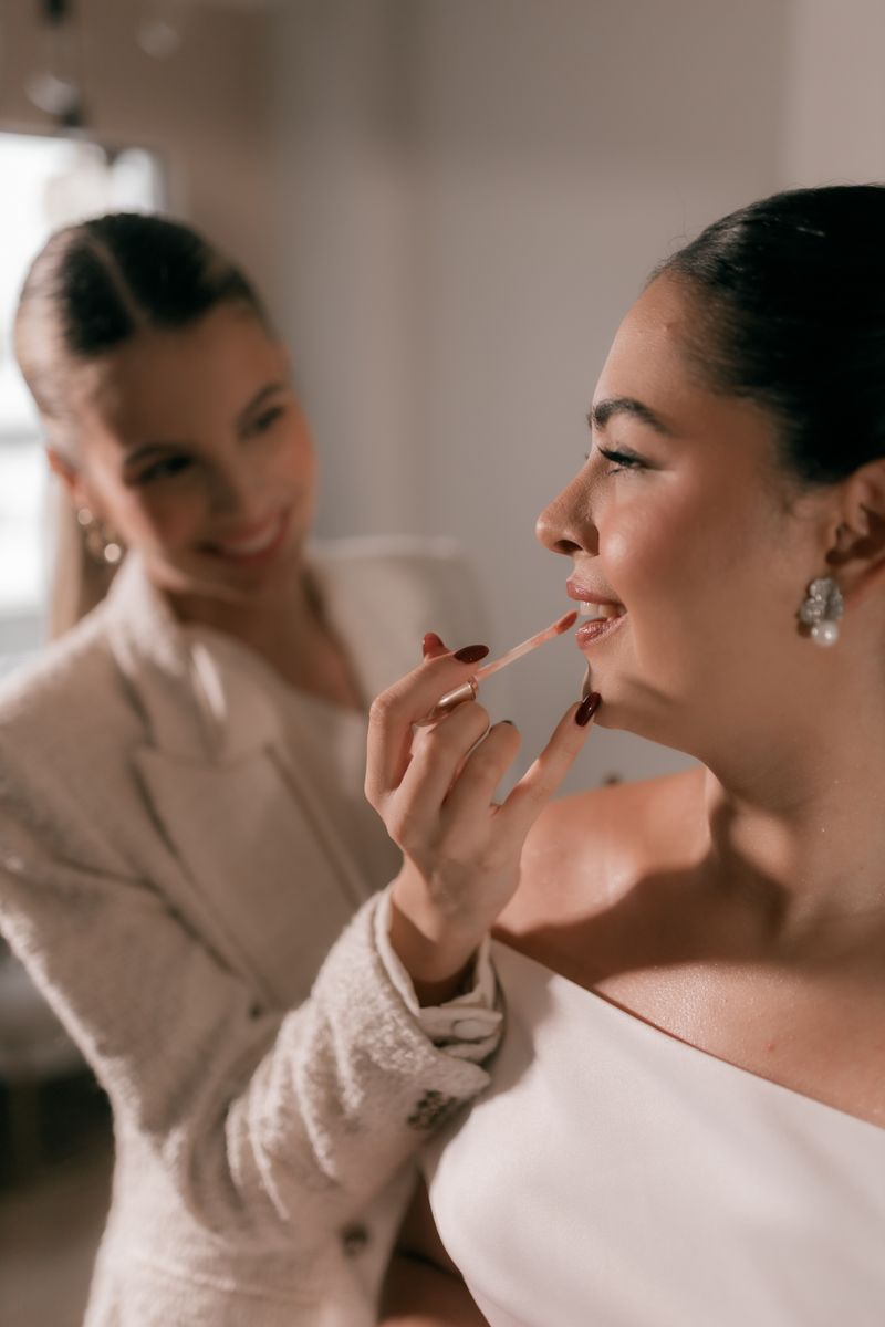 A bride laughing as her artist applies lipstick