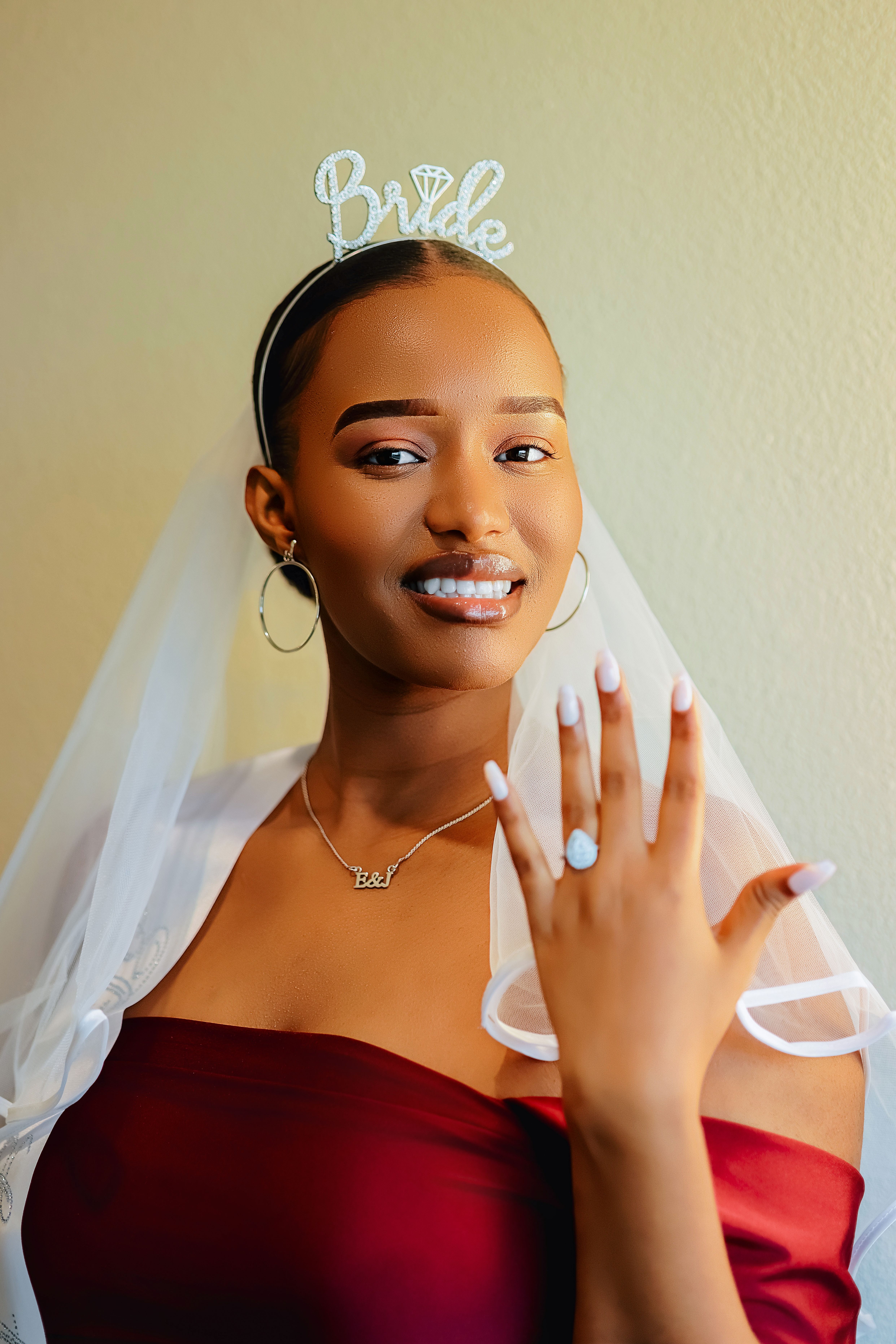 Beautiful bride in an elegant dress proudly displaying her engagement ring with a joyful smile.
