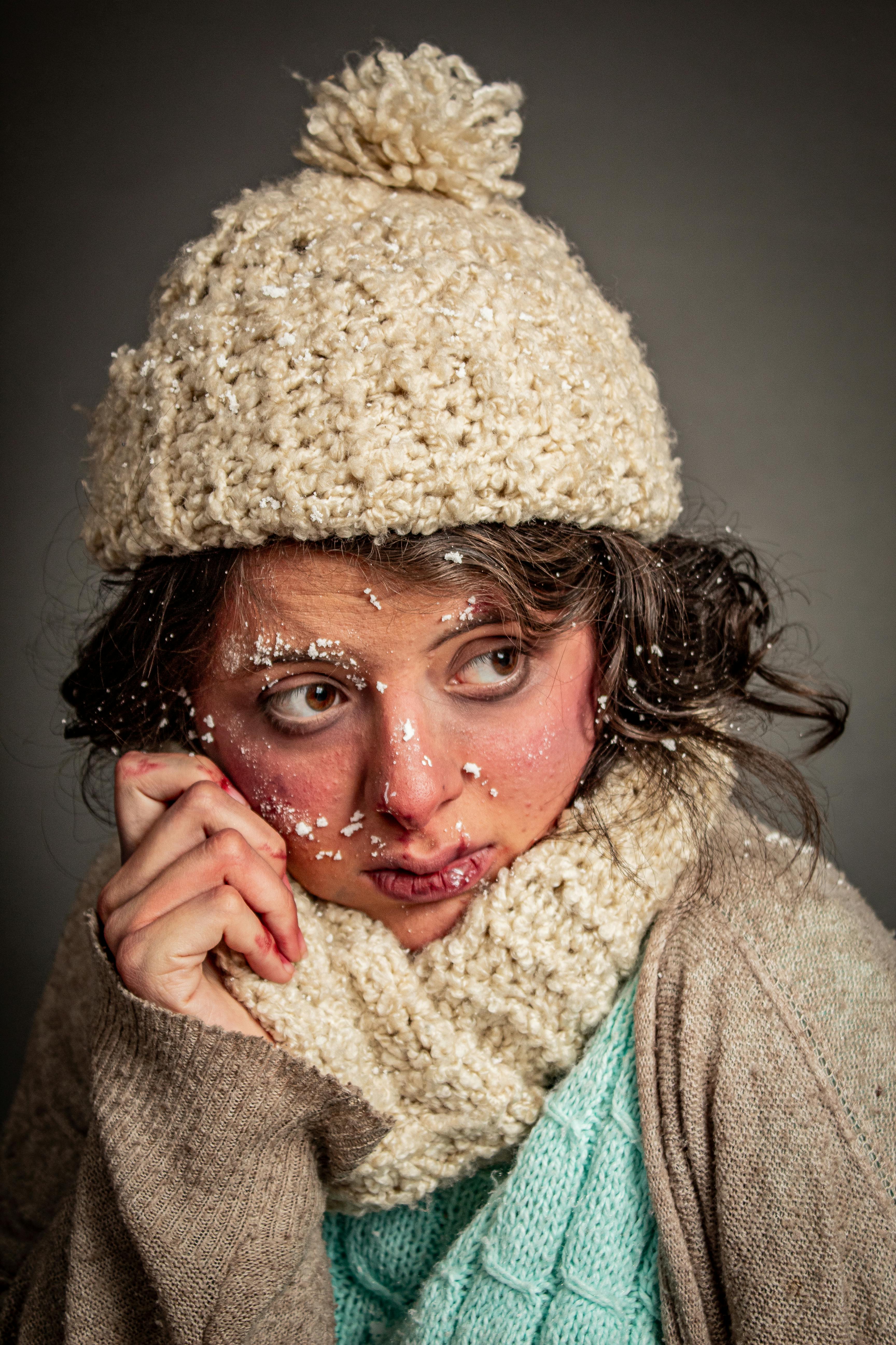 De franc Primer pla d'una dona amb un barret i una bufanda d'hivern, amb flocs de neu a la cara. Foto d'estoc