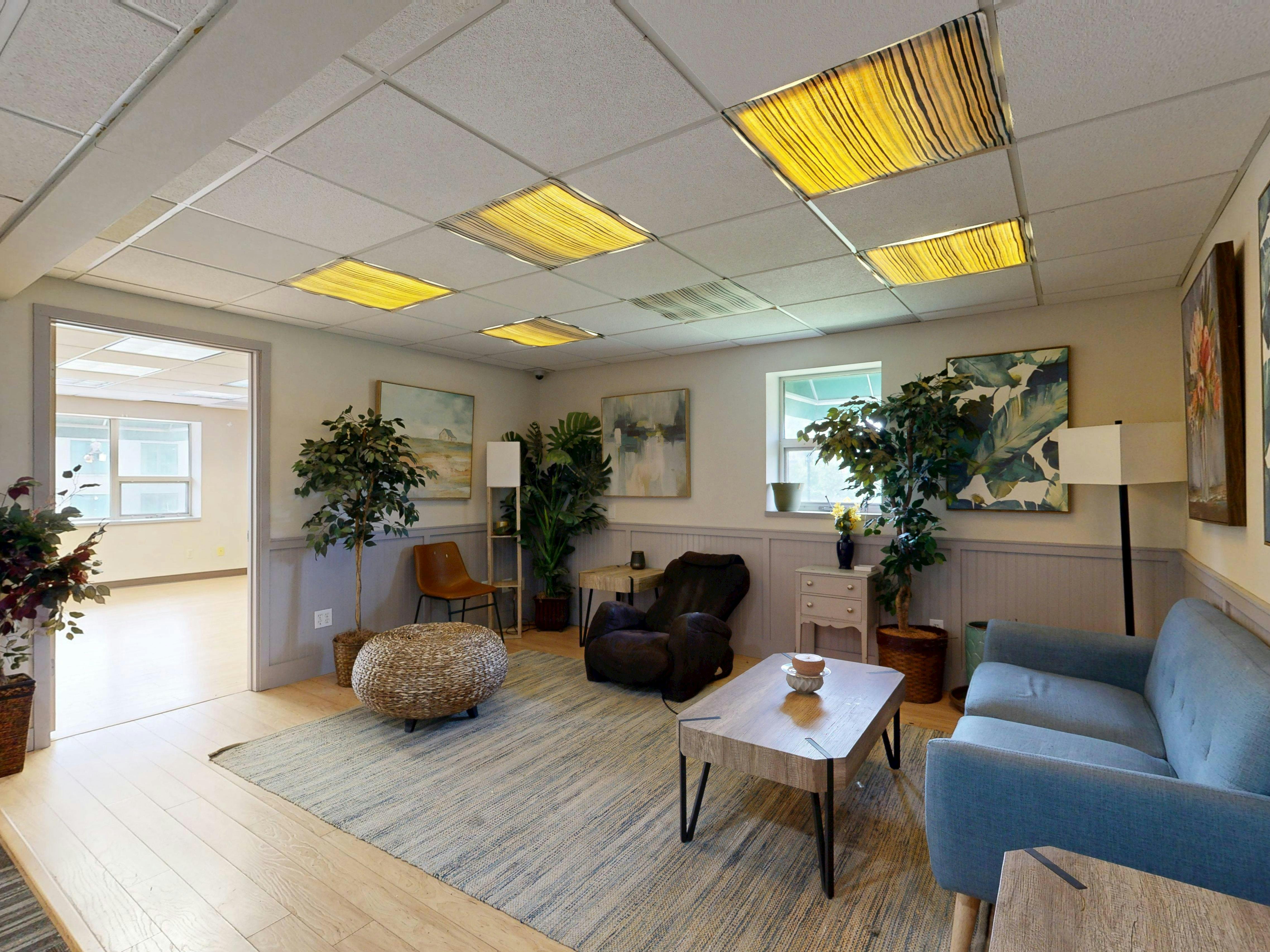 Cozy small living room with floor seating and plant stand in urban apartment