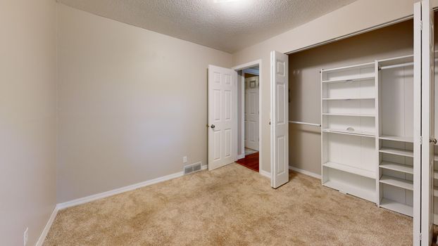 Spacious empty room with open closet and doors, ready for furnishing.