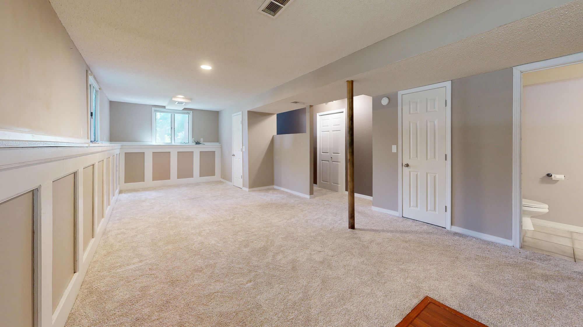 A spacious, finished modern basement with recessed lighting and carpet flooring