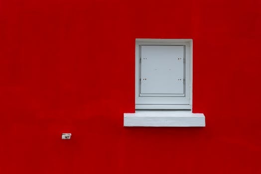 An artistic, vibrant red wall with a minimalist white window, creating a striking contrast.