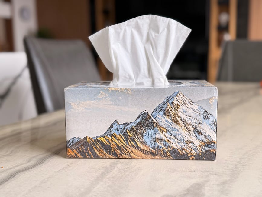 A tissue box with a mountain landscape design, placed on a marble table indoors.