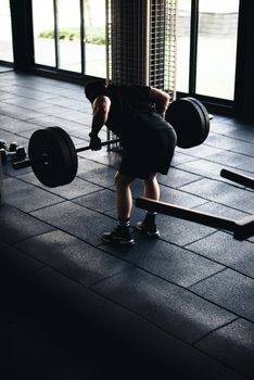 A man lifting heavy weights in a dimly lit gym, showcasing strength and determination.