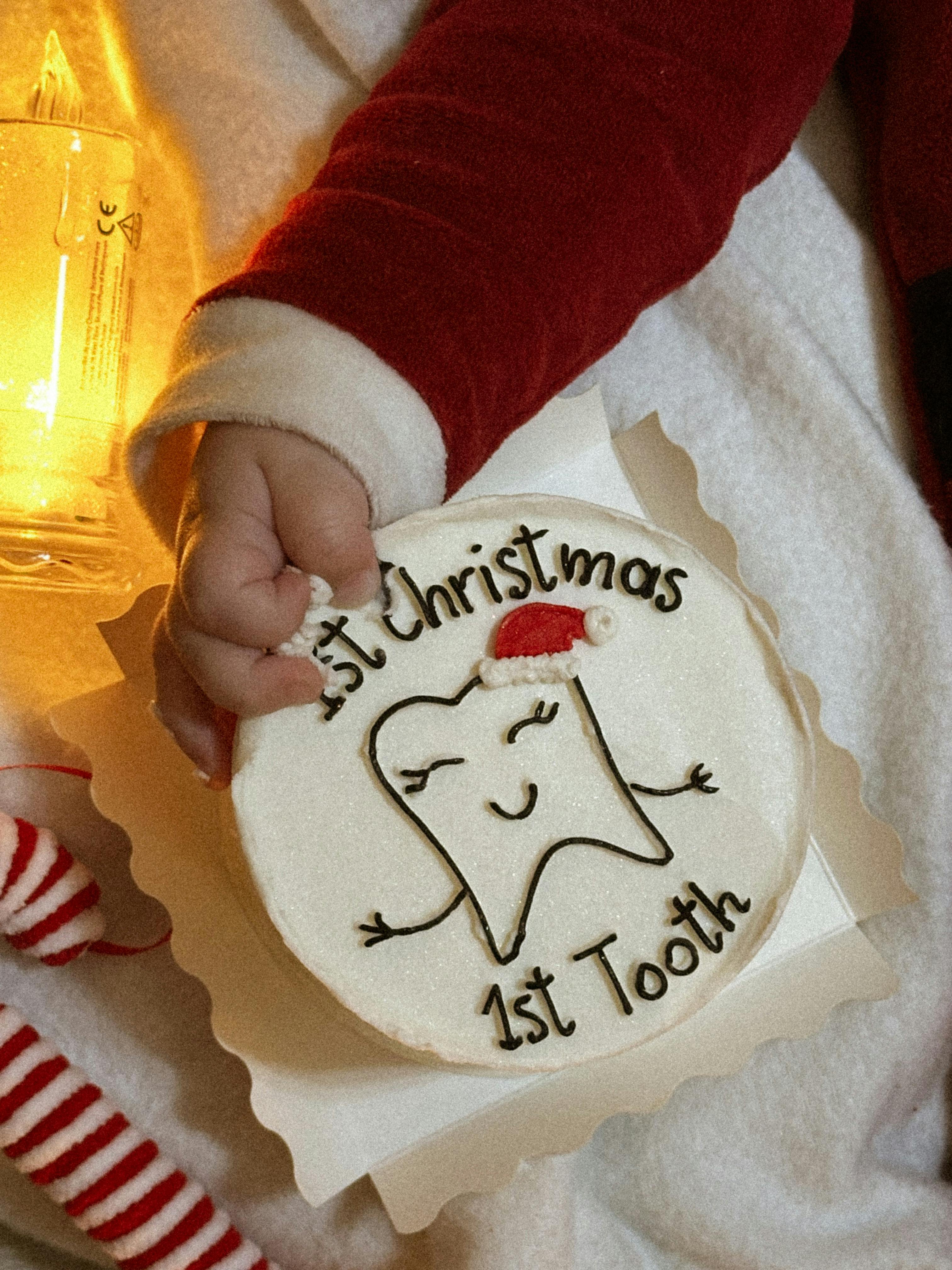 Baby in Santa suit holding decoration celebrating first Christmas and tooth.