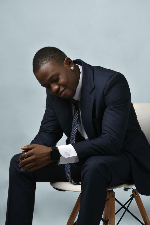 Free Businessman in a suit sitting pensively on a chair against a plain background. Stock Photo