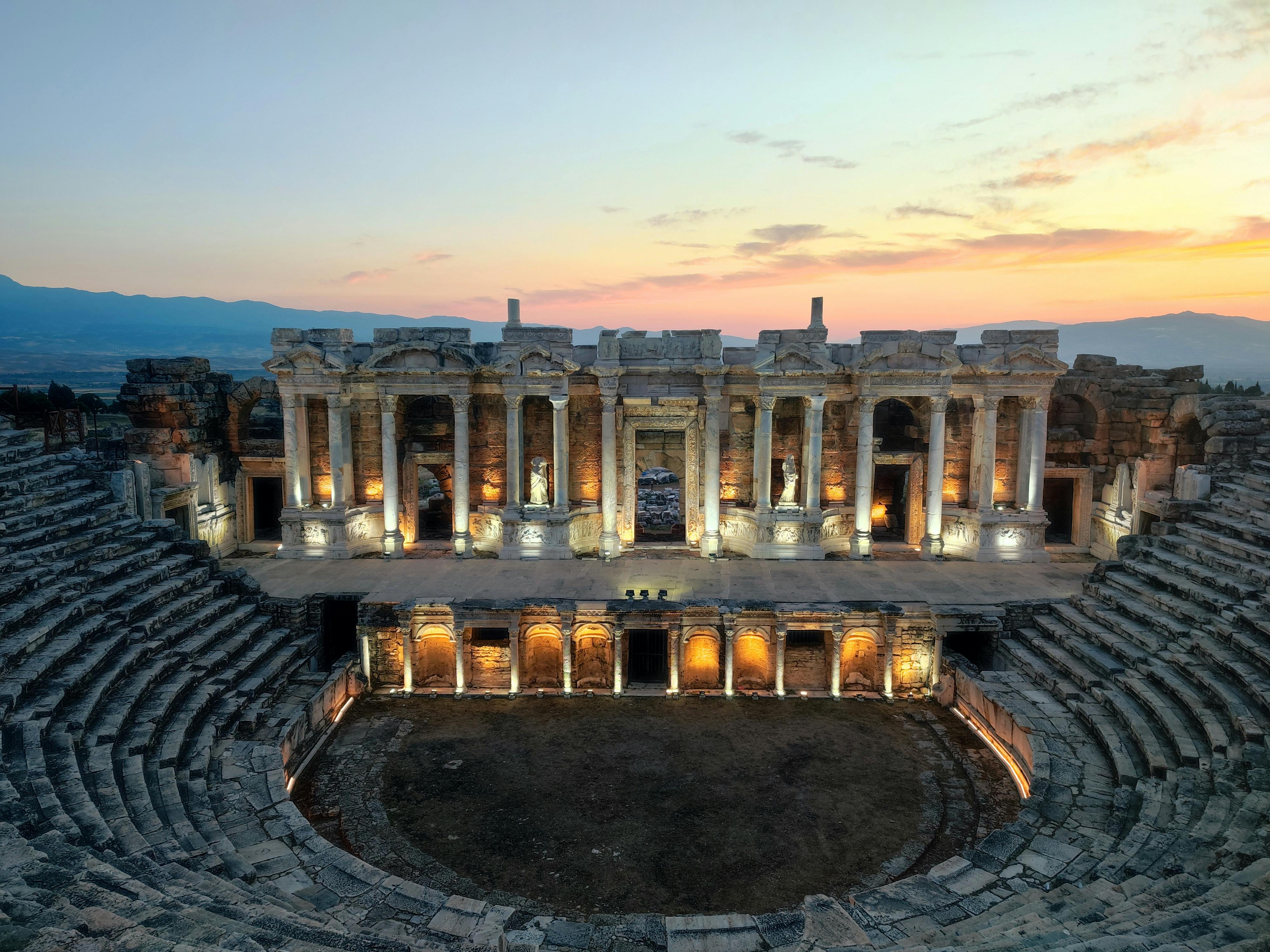 Ücretsiz Muhteşem bir gün batımı altında sıcak ışıklarla aydınlatılmış antik Hierapolis tiyatrosunun görkemli manzarası. Stok Fotoğraflar