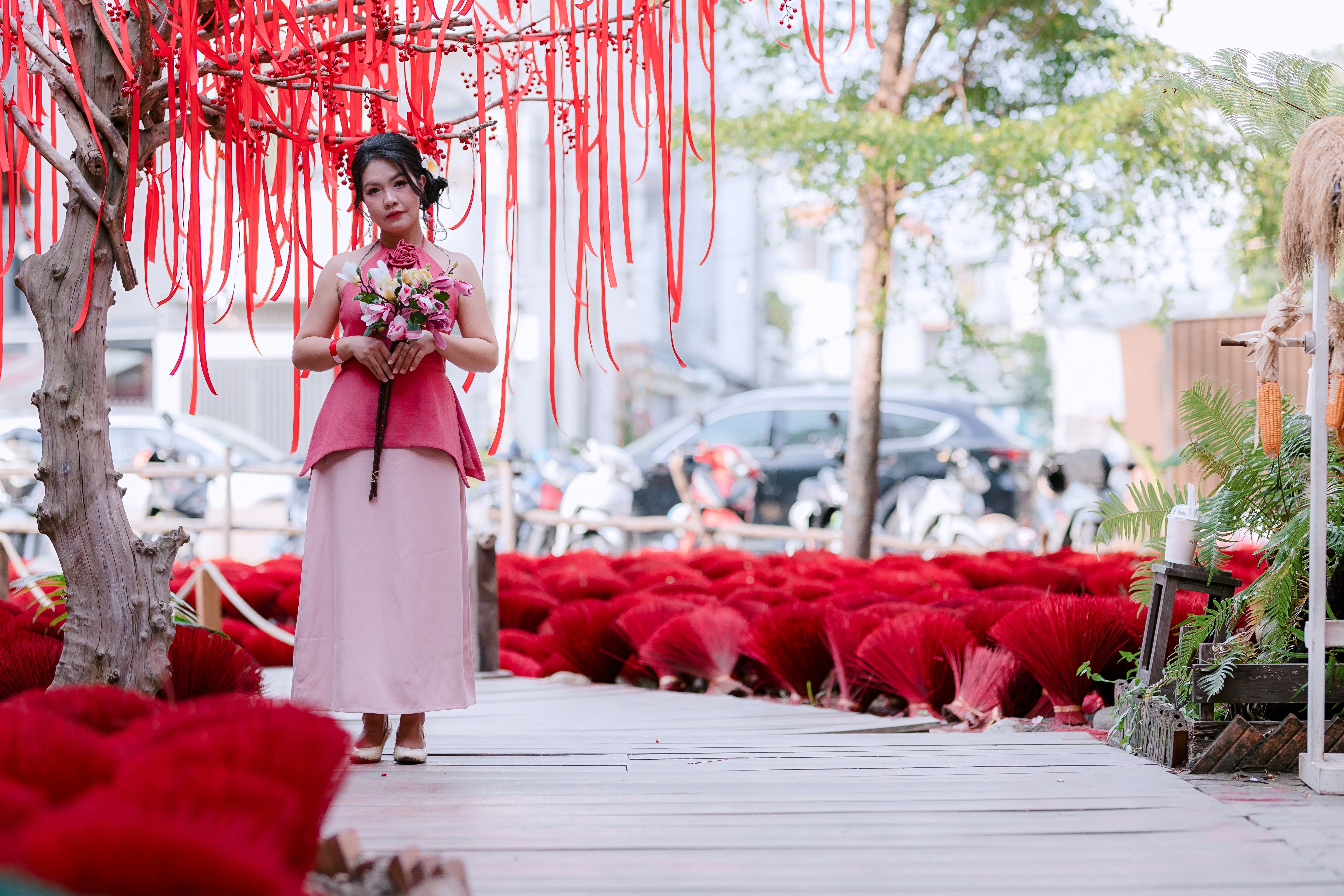 Woman in traditional dress under red ribbon tree · Free Stock Photo