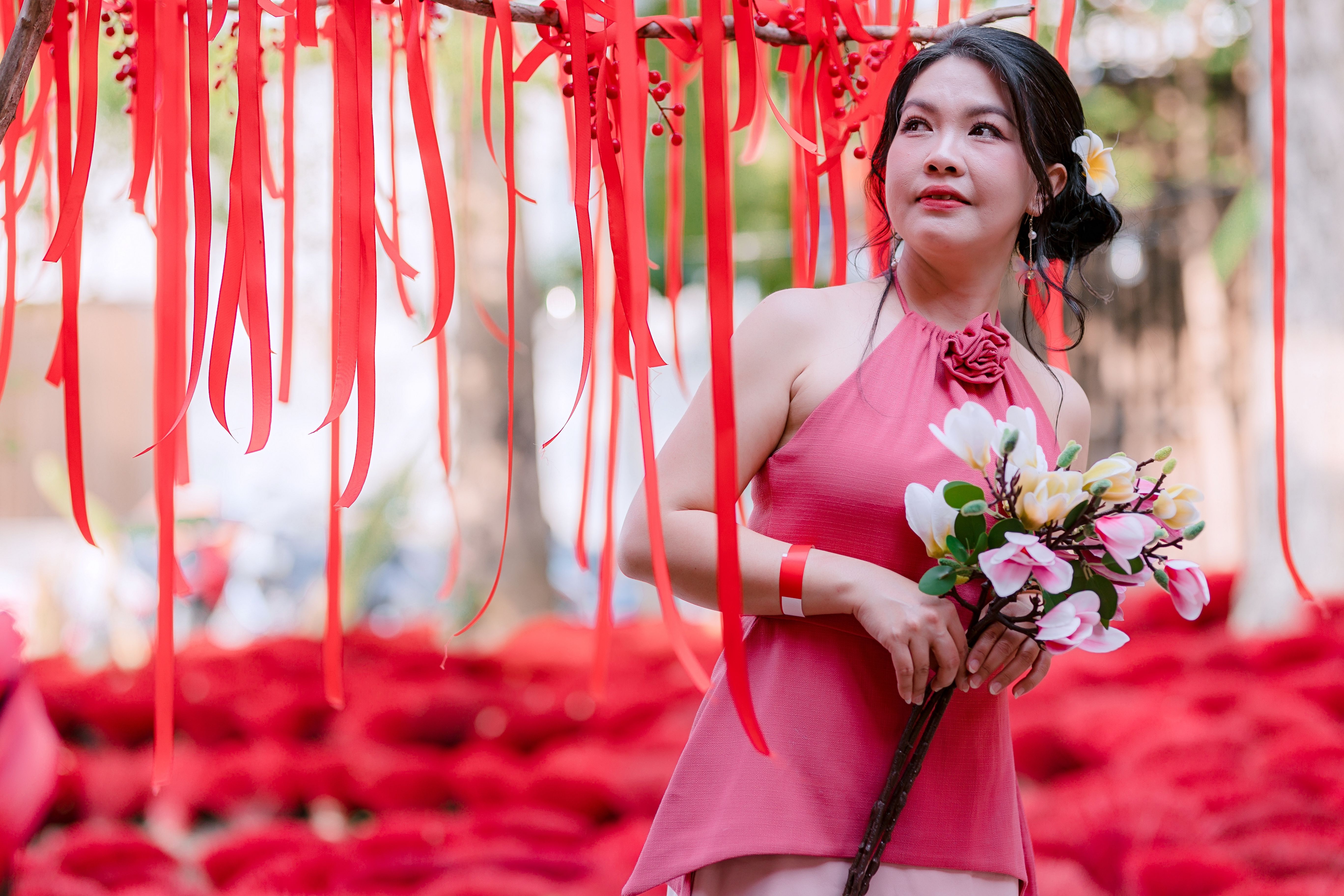 Woman in Pink Dress Holding Flowers with Red Ribbons · Free Stock Photo