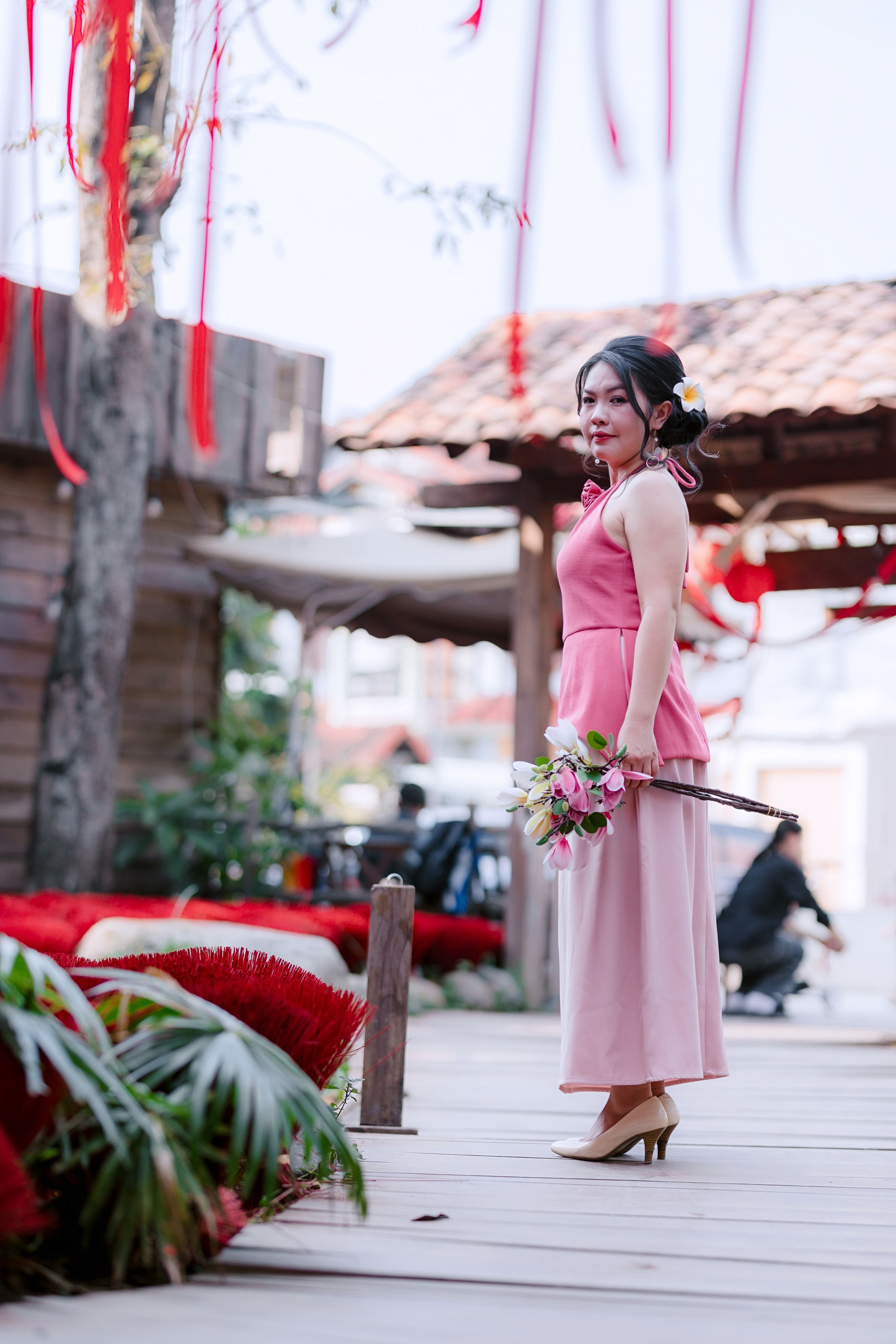 Elegant Woman in Pink Dress Holding Flowers Outdoors · Free Stock Photo
