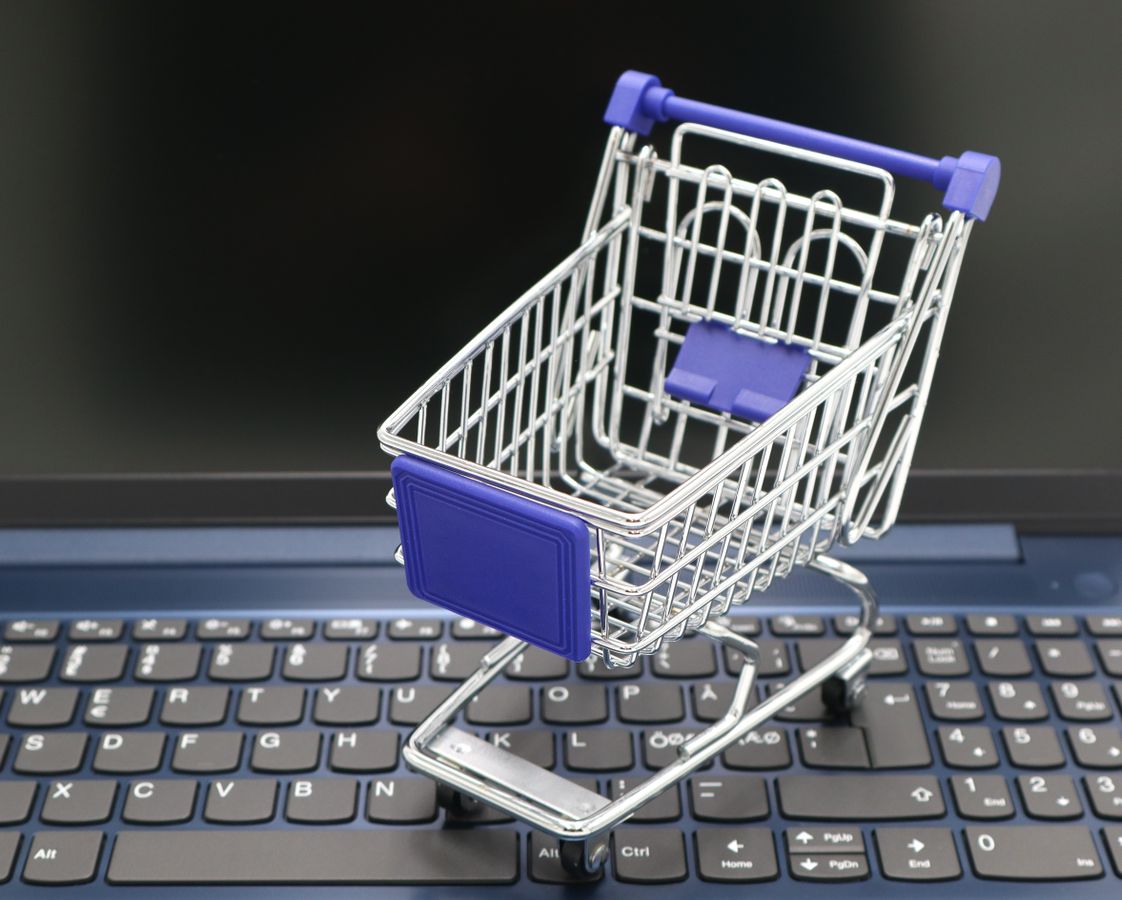Miniature shopping cart on a laptop representing online commerce