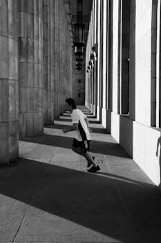 A runner speeds through a shadowed architectural column corridor.