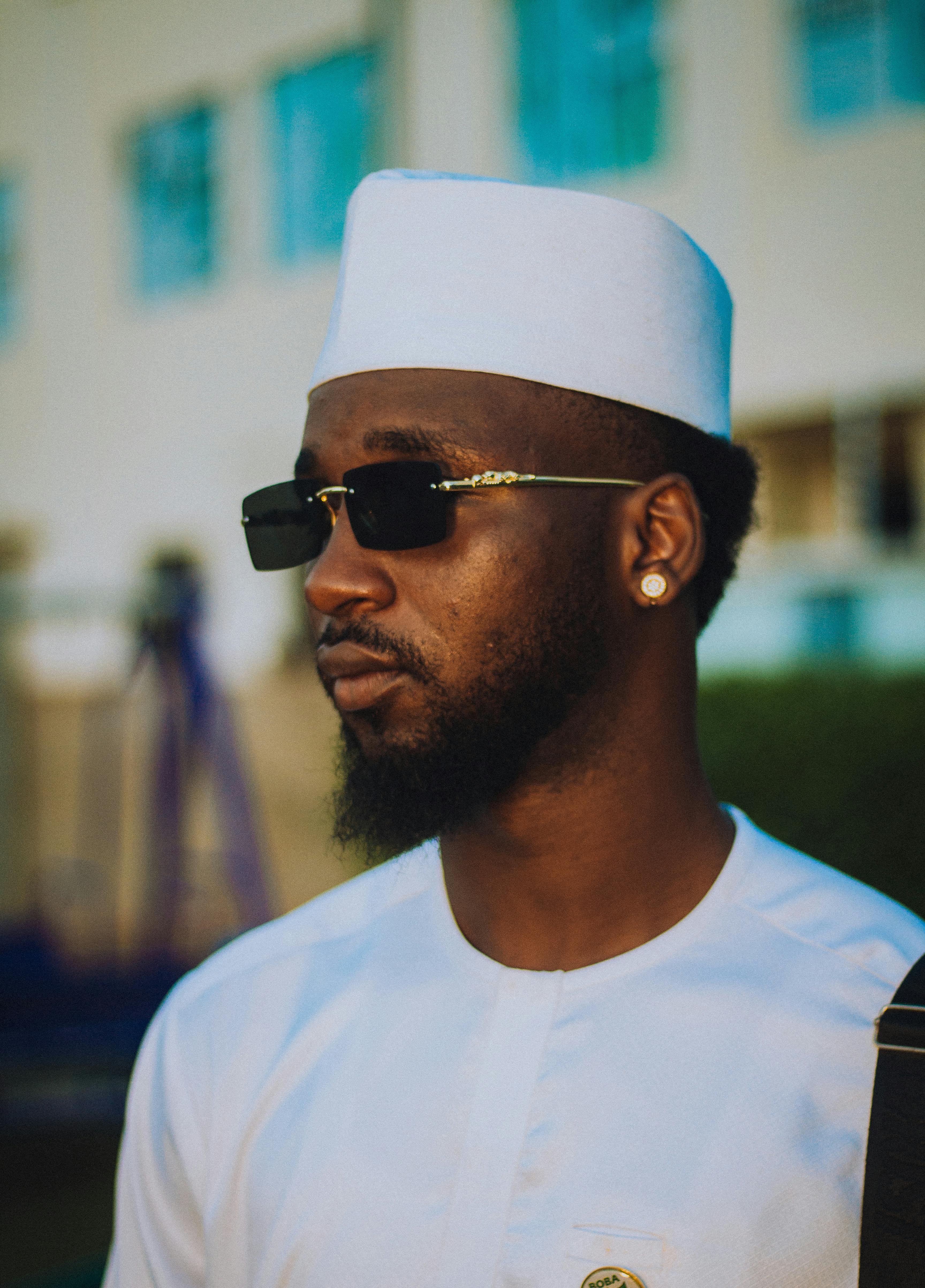 De franc Un home elegant amb ulleres de sol i vestit blanc tradicional, que traspua confiança. Foto d'estoc