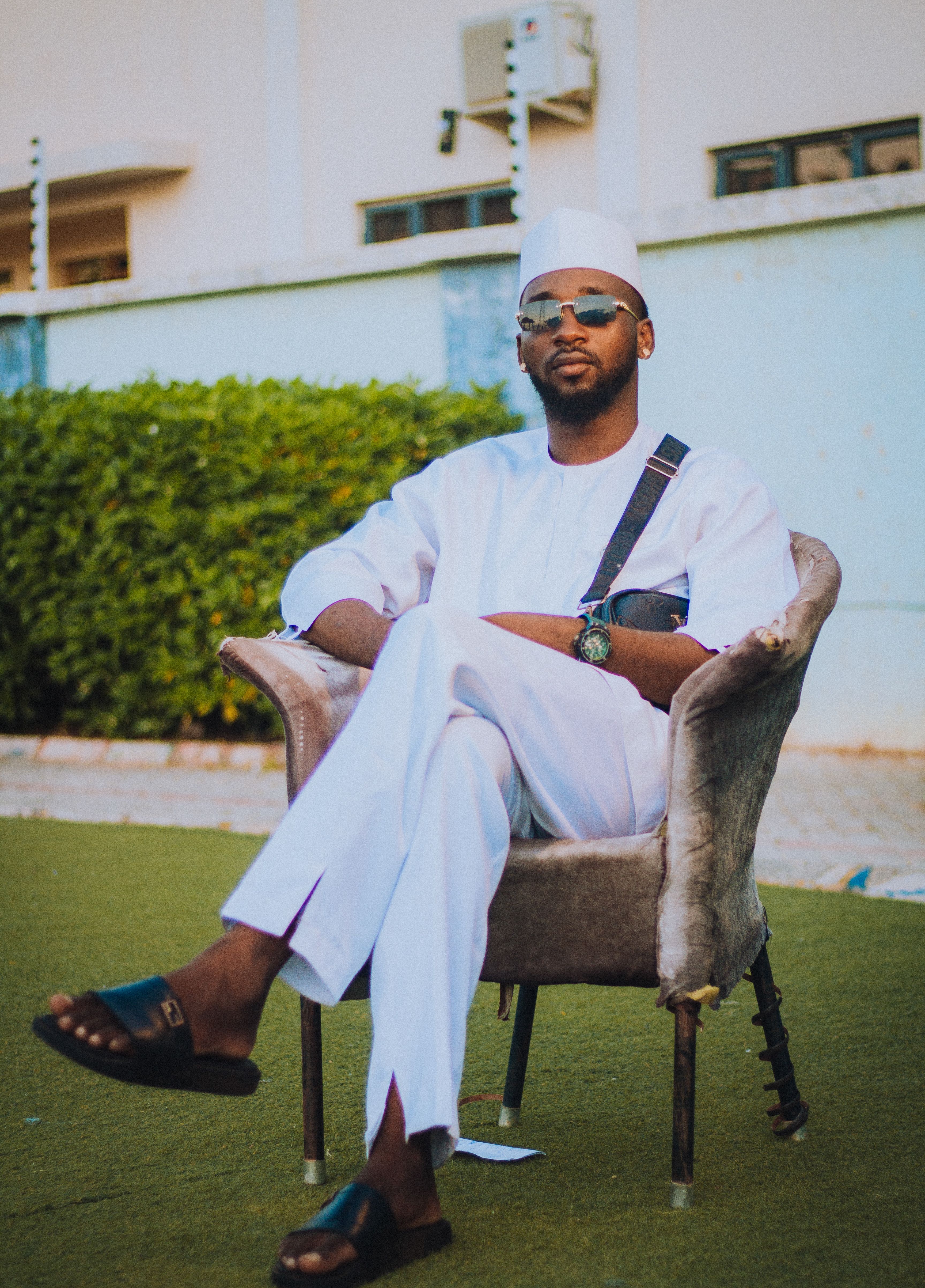Confident man seated outdoors in traditional attire, showcasing modern style and serenity.