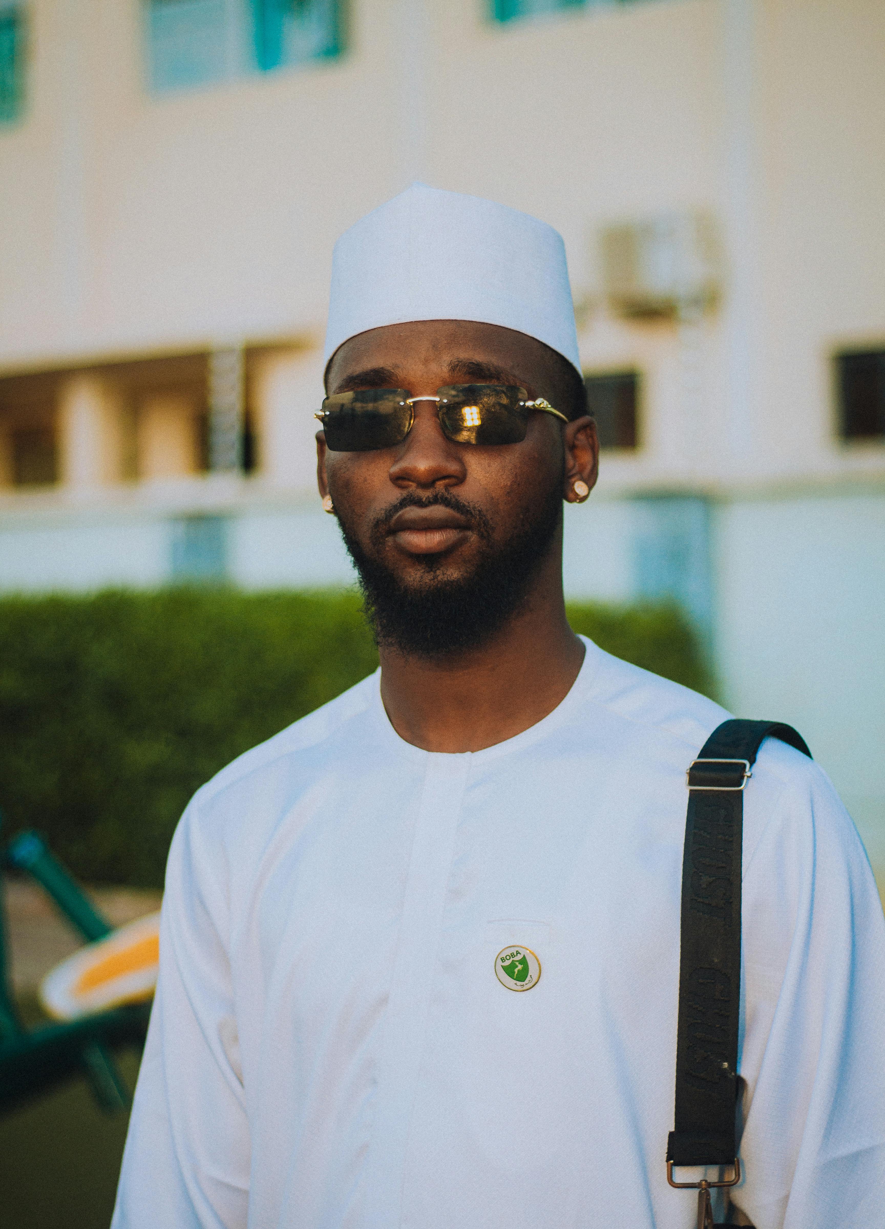 De franc Home amb vestit blanc tradicional, ulleres de sol i una postura segura a l'aire lliure. Foto d'estoc