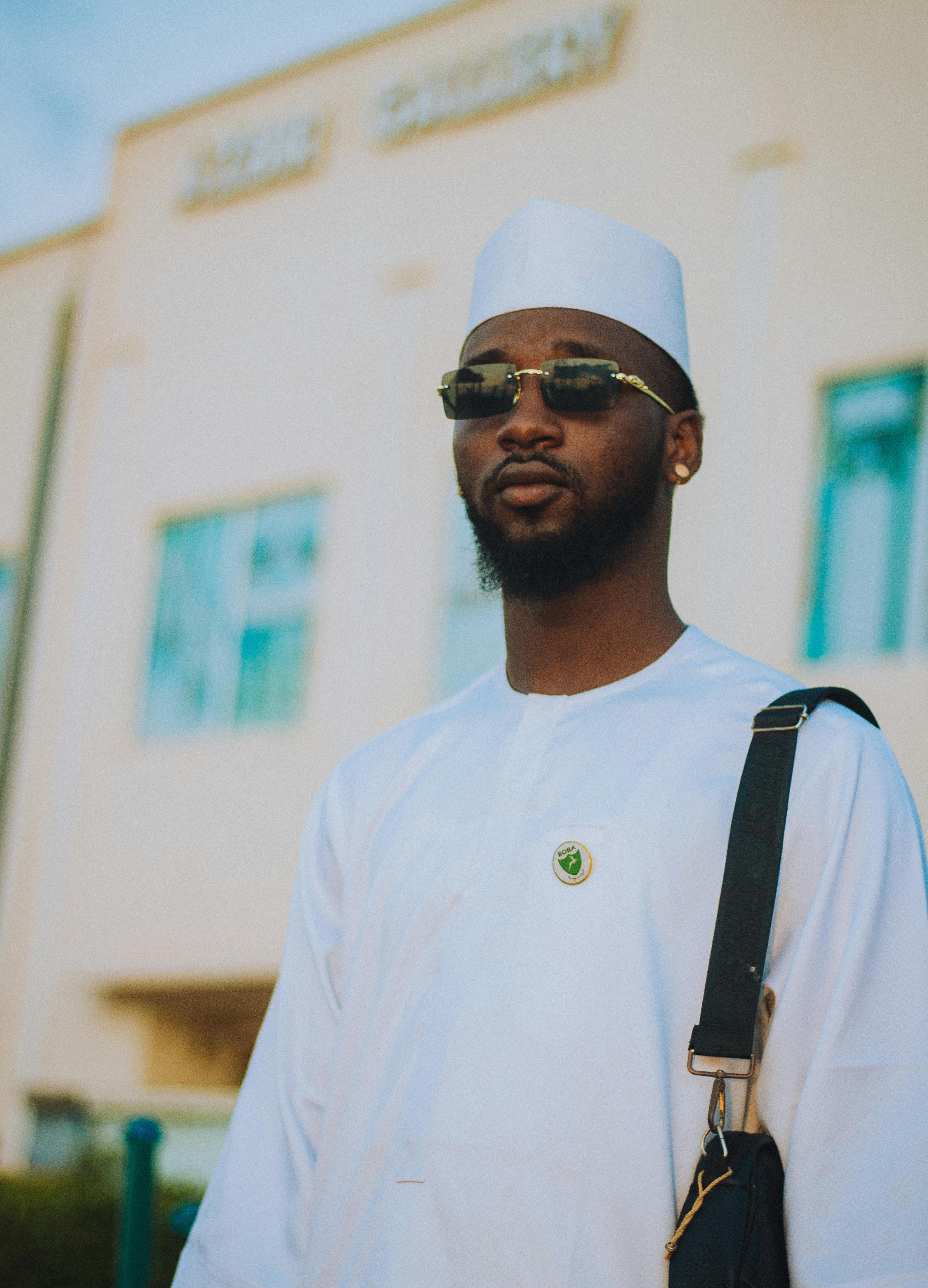 De franc Retrat d'un home elegant amb vestit tradicional blanc i ulleres de sol a l'aire lliure. Foto d'estoc